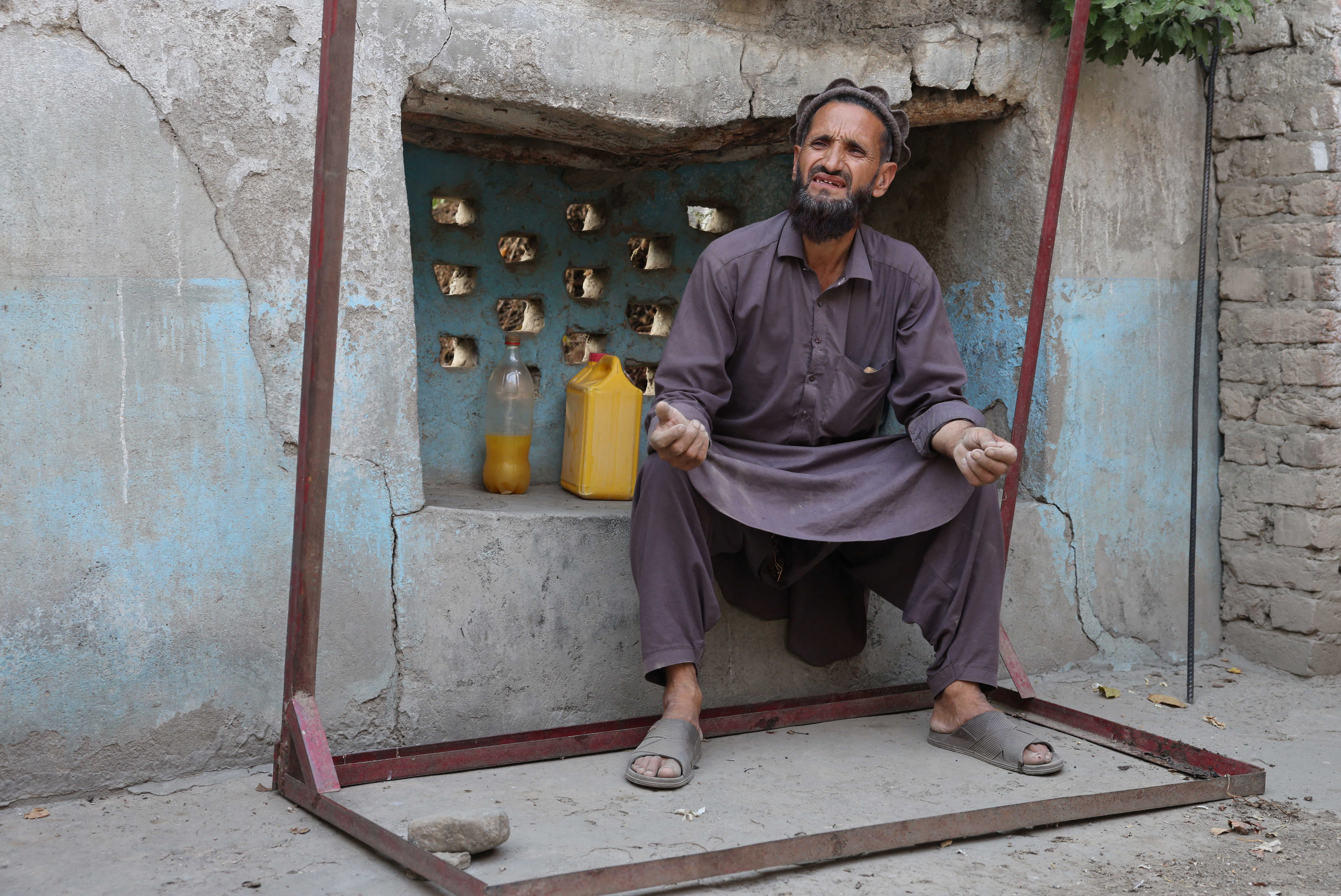 Abdul Ghafar sits at his partially damaged house as he speaks during an interview with Reuters, in Bambakot village