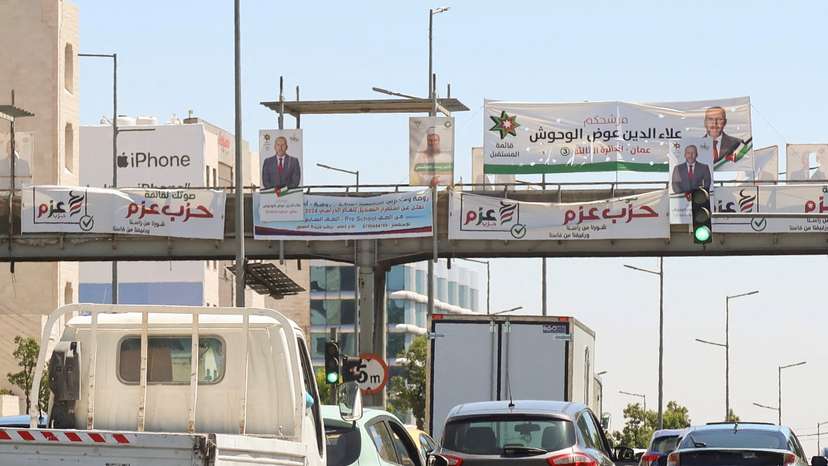 Cars pass near banners and pictures of candidates running in the country's parliamentary election in Amman