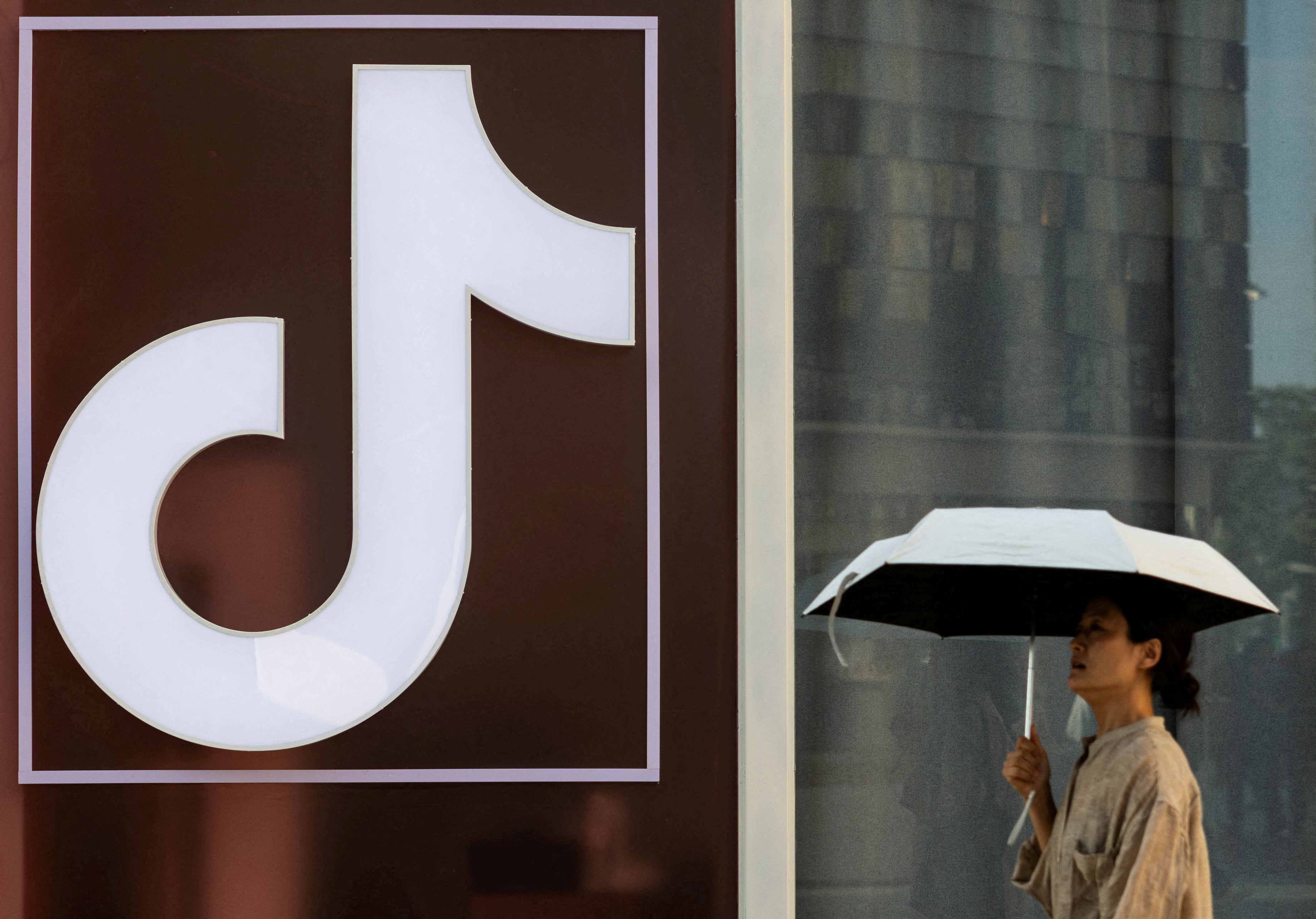 FILE PHOTO: A woman walks past a logo of Tik Tok social network on Wangfujing street in Beijing