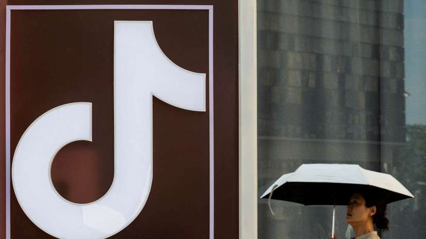FILE PHOTO: A woman walks past a logo of Tik Tok social network on Wangfujing street in Beijing