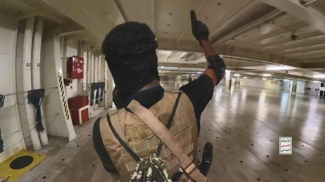 Houthi fighter holds up a pistol in the cargo area of the Galaxy Leader cargo ship in the Red Sea