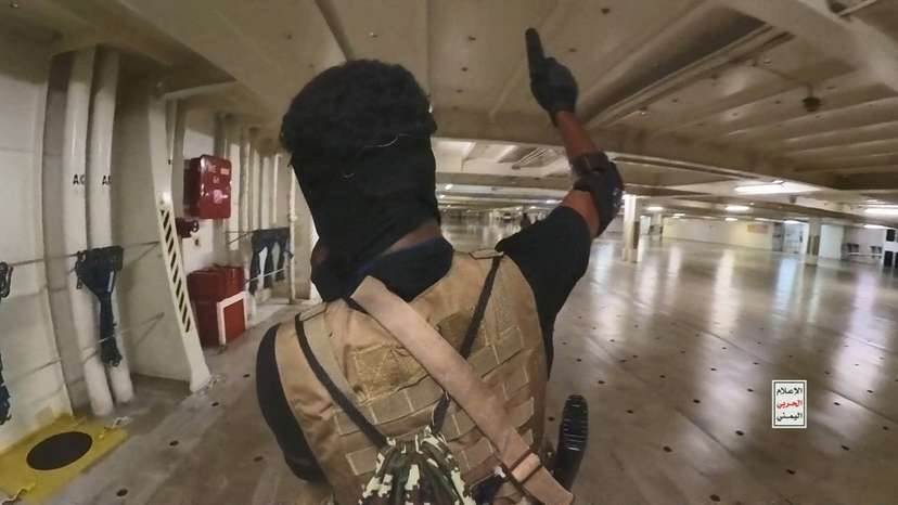 Houthi fighter holds up a pistol in the cargo area of the Galaxy Leader cargo ship in the Red Sea