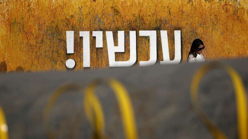 Woman walks near installation with yellow ribbons representing the struggle to release the hostages kidnapped during the deadly October 7, 2023 attack by Hamas, in Tel Aviv