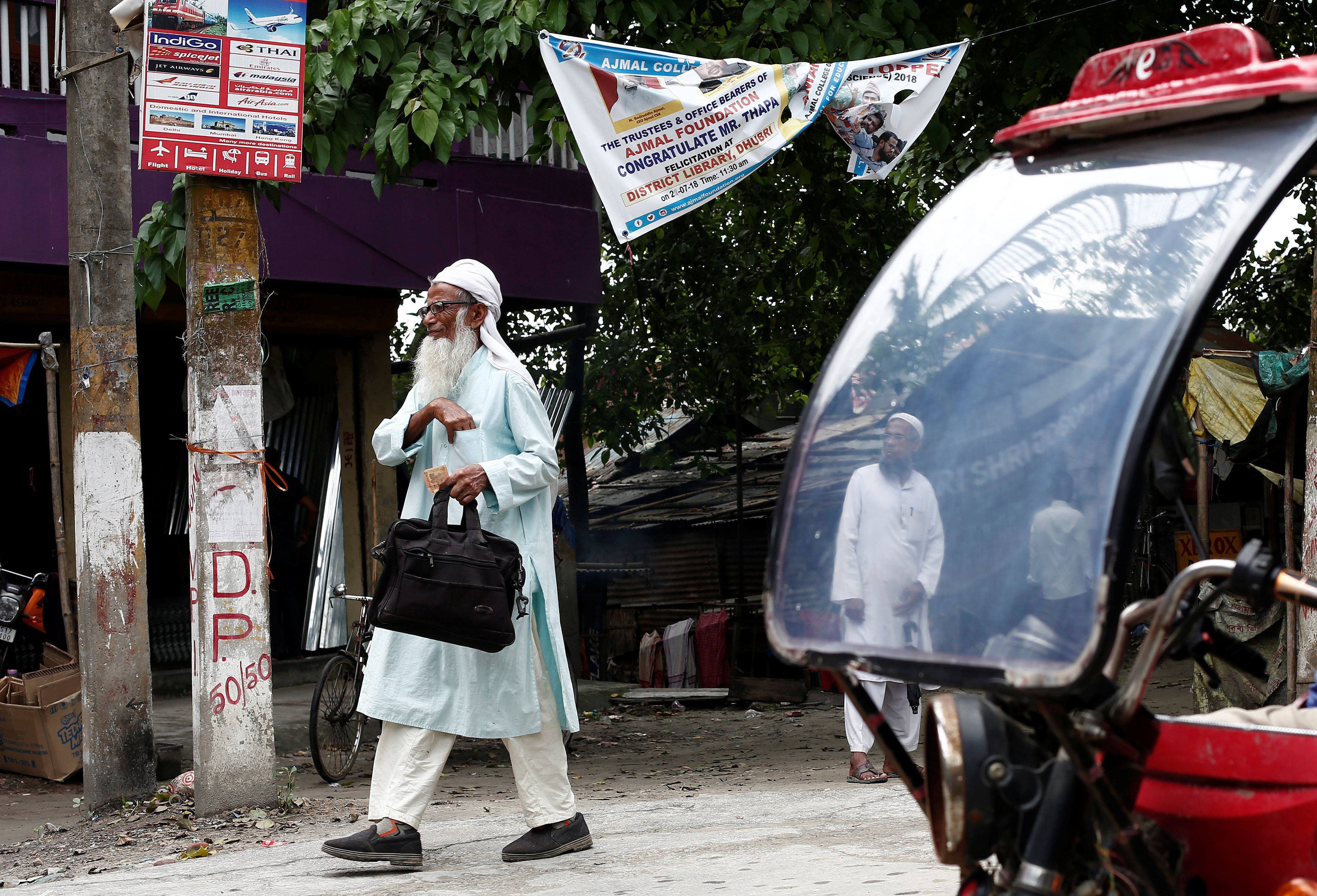 FILE PHOTO: A man walks past an auto rickshaw in Dhubri district, in the northeastern state of Assam