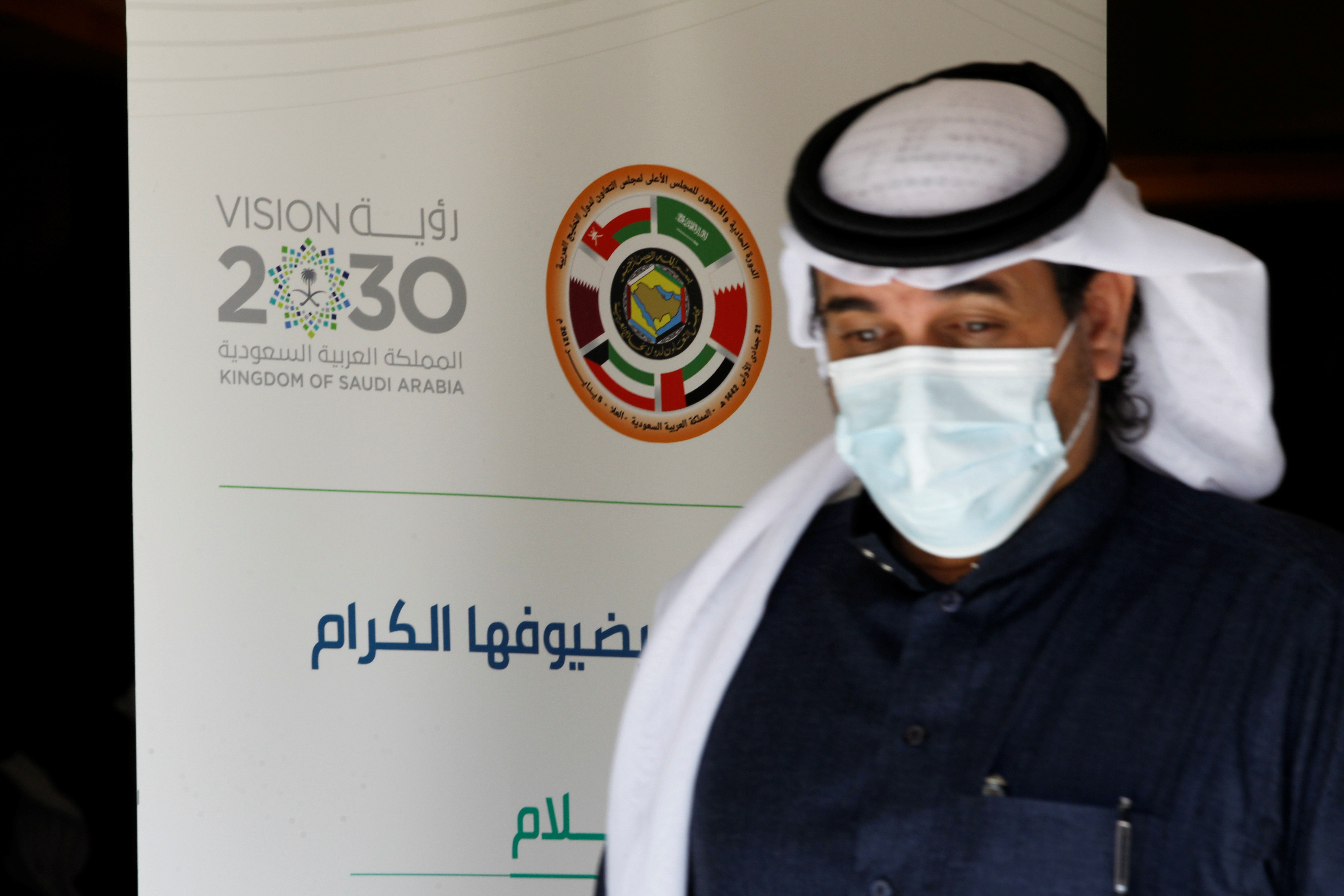 A journalist walks past the logo of the Gulf Cooperation Council (GCC) at the media centre ahead of the 41st summit in Al-Ula