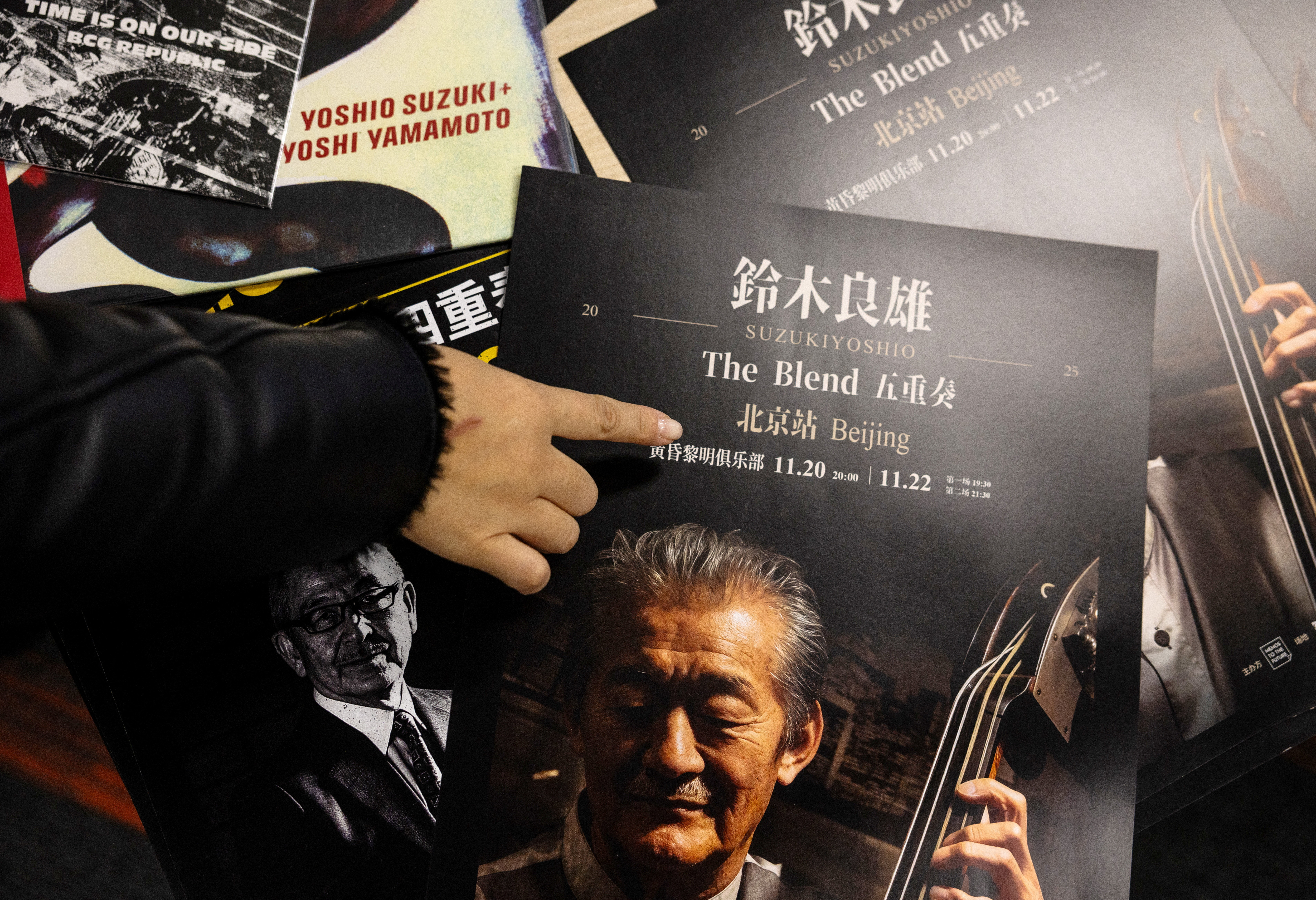 A woman points to an advertisement poster for a canceled concert by Japanese musician Yoshio Suzuki in Beijing
