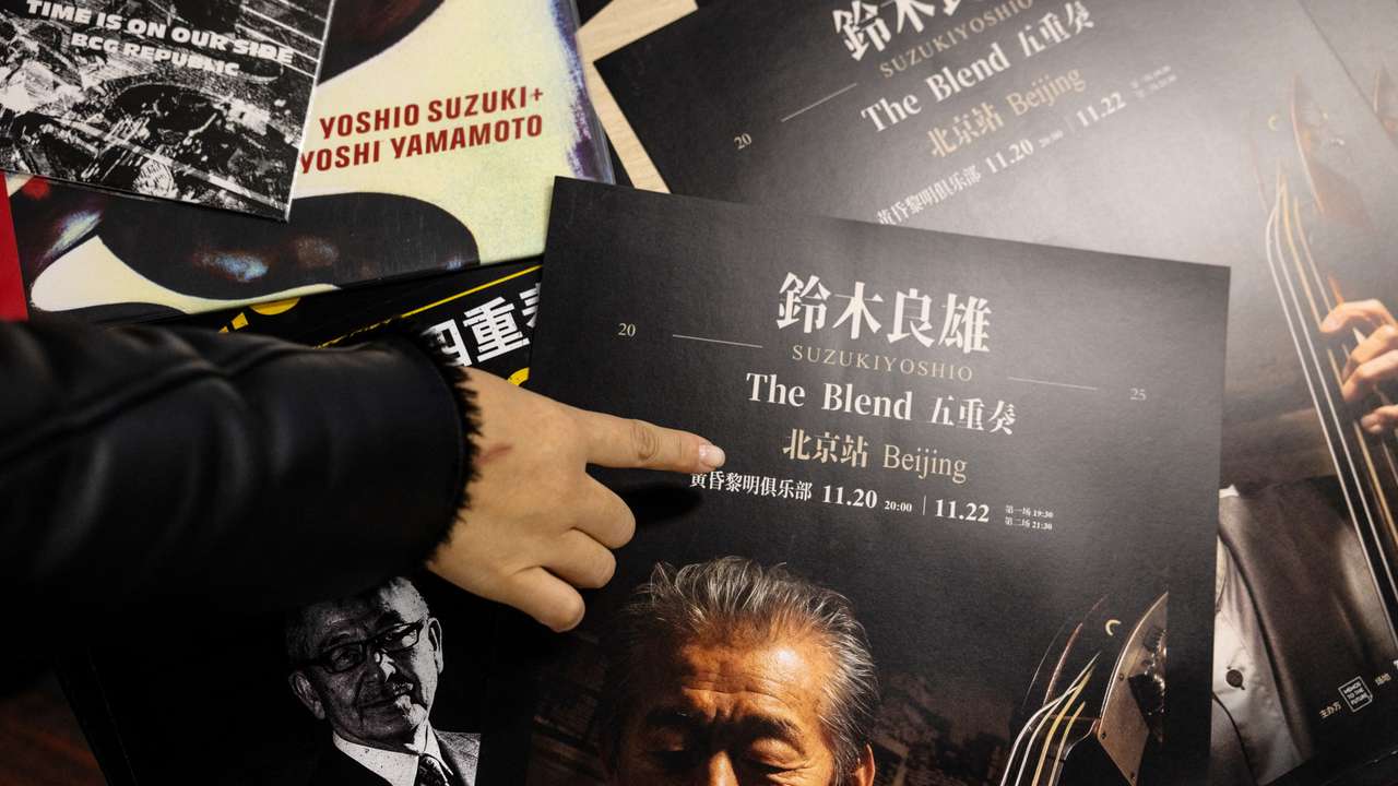 A woman points to an advertisement poster for a canceled concert by Japanese musician Yoshio Suzuki in Beijing