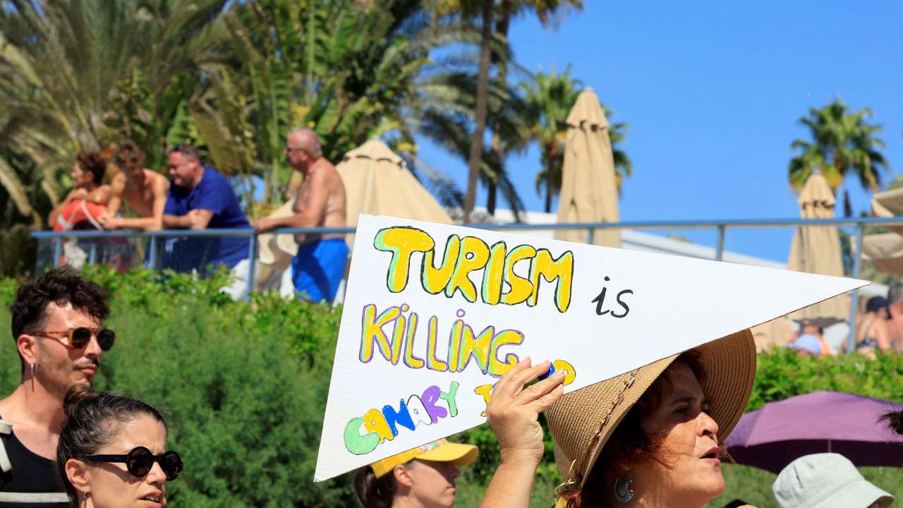 A woman shows a sign during a demonstration for a change in the tourism model in the Canary Islands