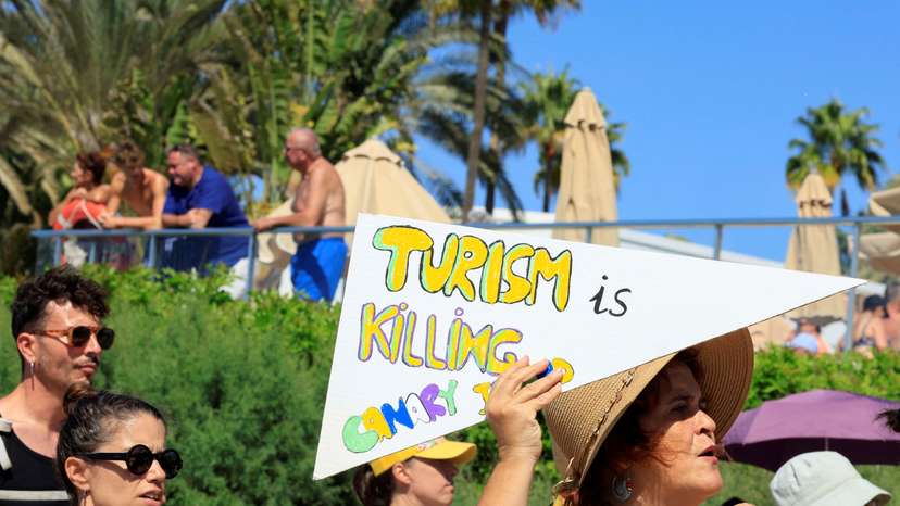 A woman shows a sign during a demonstration for a change in the tourism model in the Canary Islands