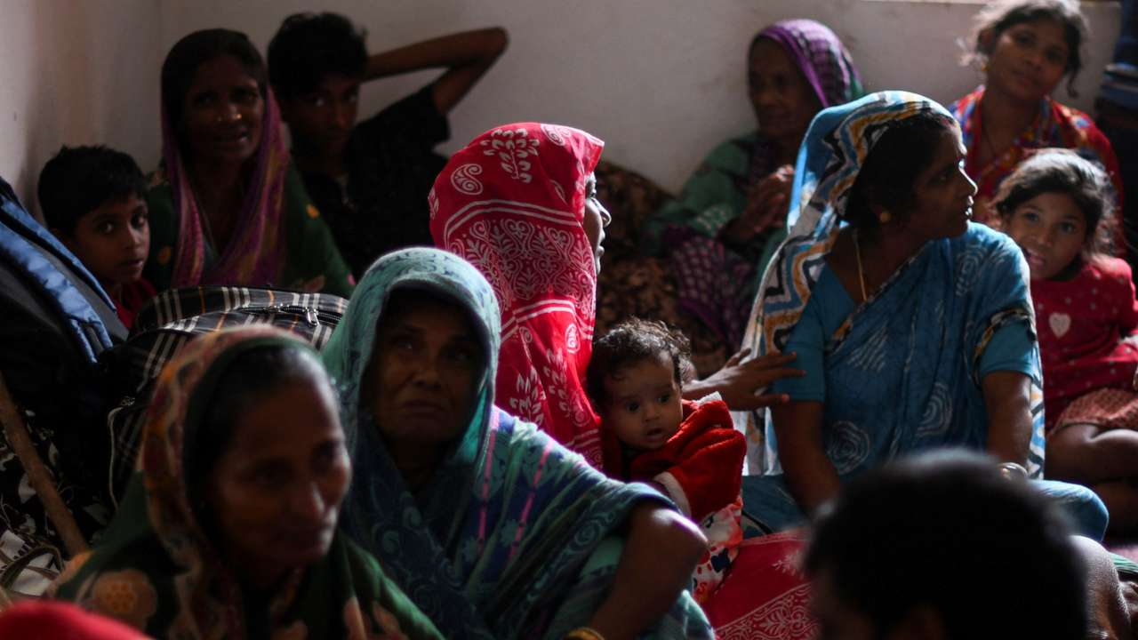 People evacuated from Amarnagar village sit inside a cyclone shelter near Dhamara fishing harbour before Cyclone Dana makes landfall, in Odisha