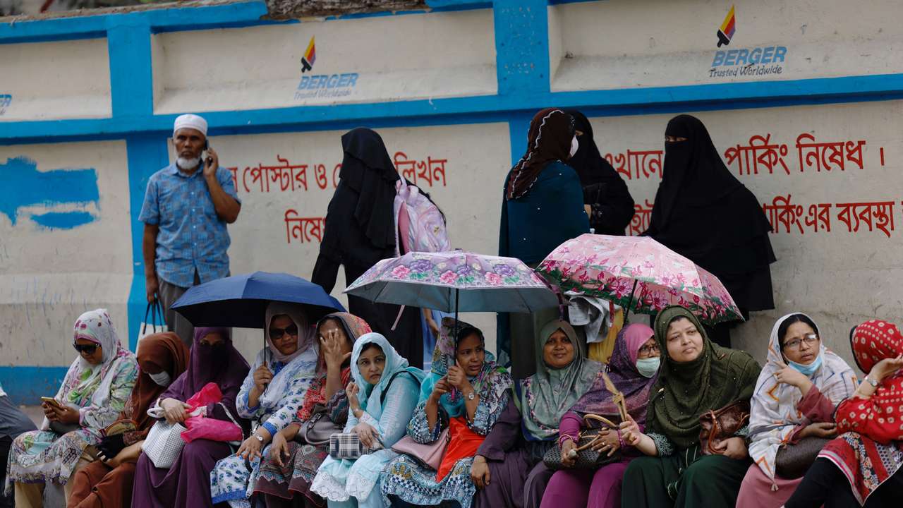 Parents wait outside a school to receive their children as schools reopen after the fall in temperature, in Dhaka