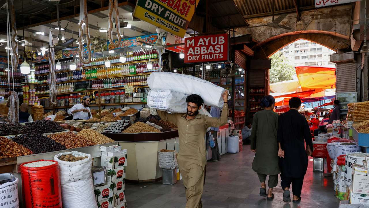 Man walks with sacks of supplies on his shoulder to deliver to a nearby shop at a market in Karachi