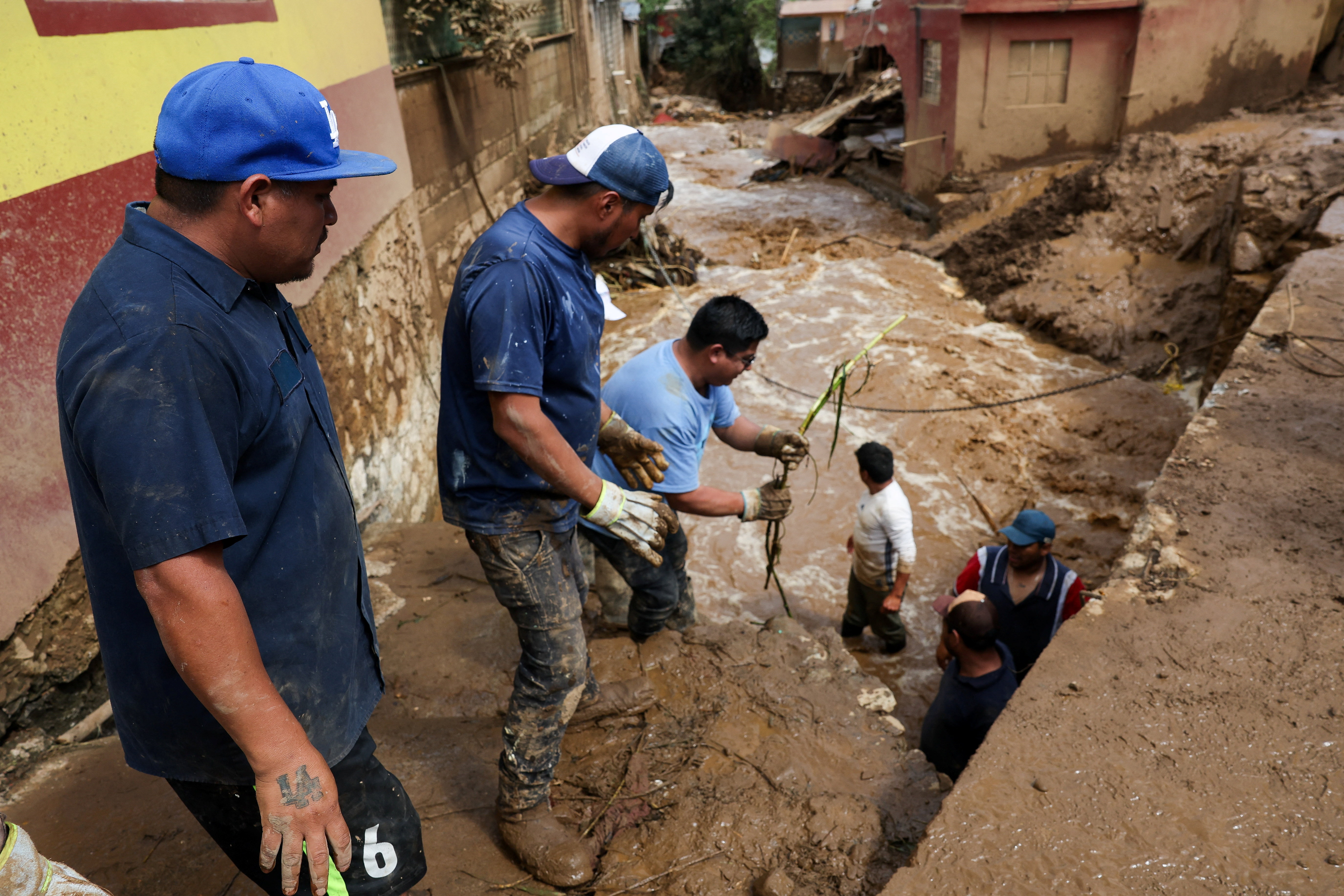 Residents work to clear the area of branches and debris following an overflowing of a river due to torrential rains, in Huauchinango
