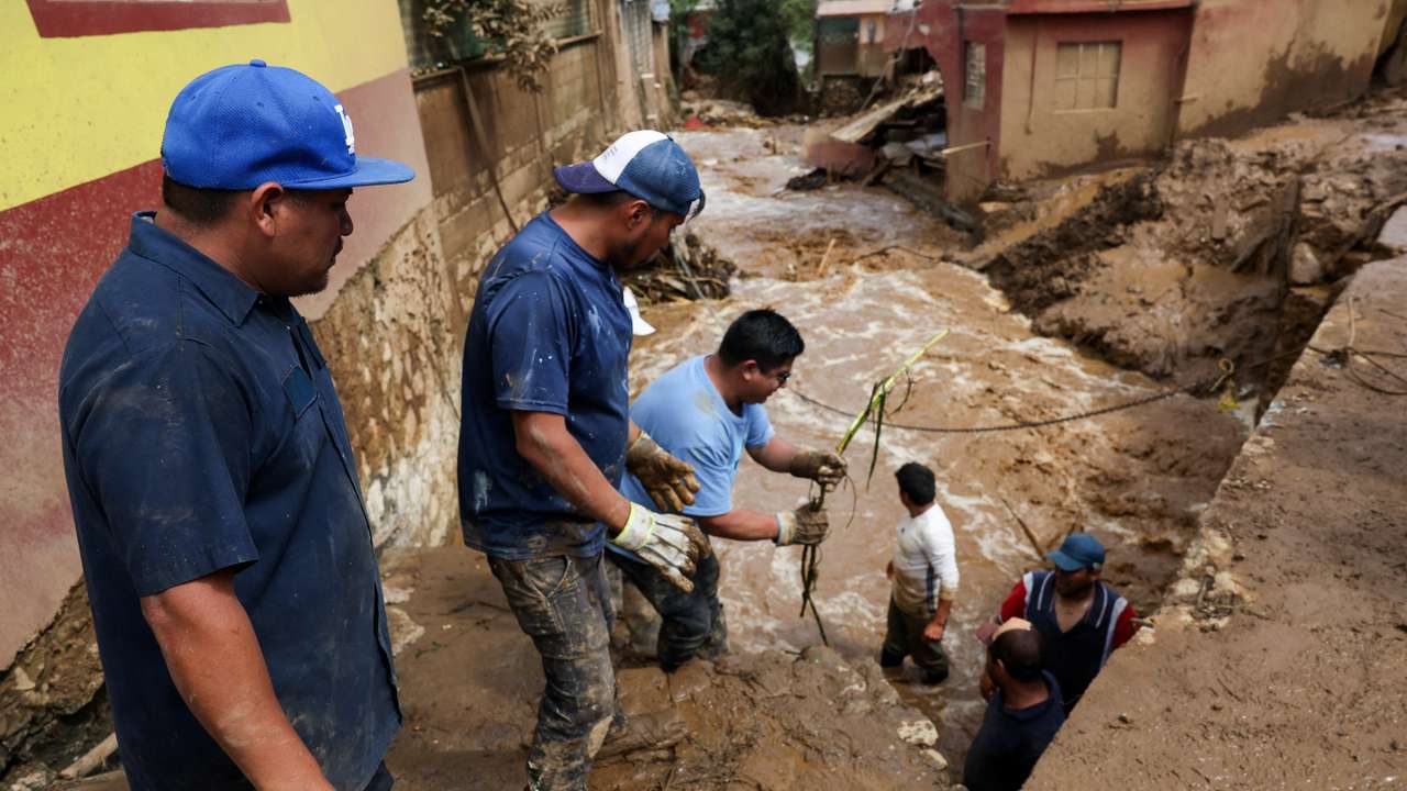 Residents work to clear the area of branches and debris following an overflowing of a river due to torrential rains, in Huauchinango