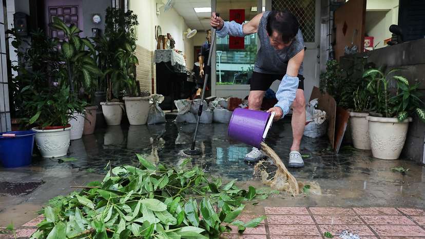 A man cleans the flood inside his home after Typhoon Krathon made landfall in Kaohsiung