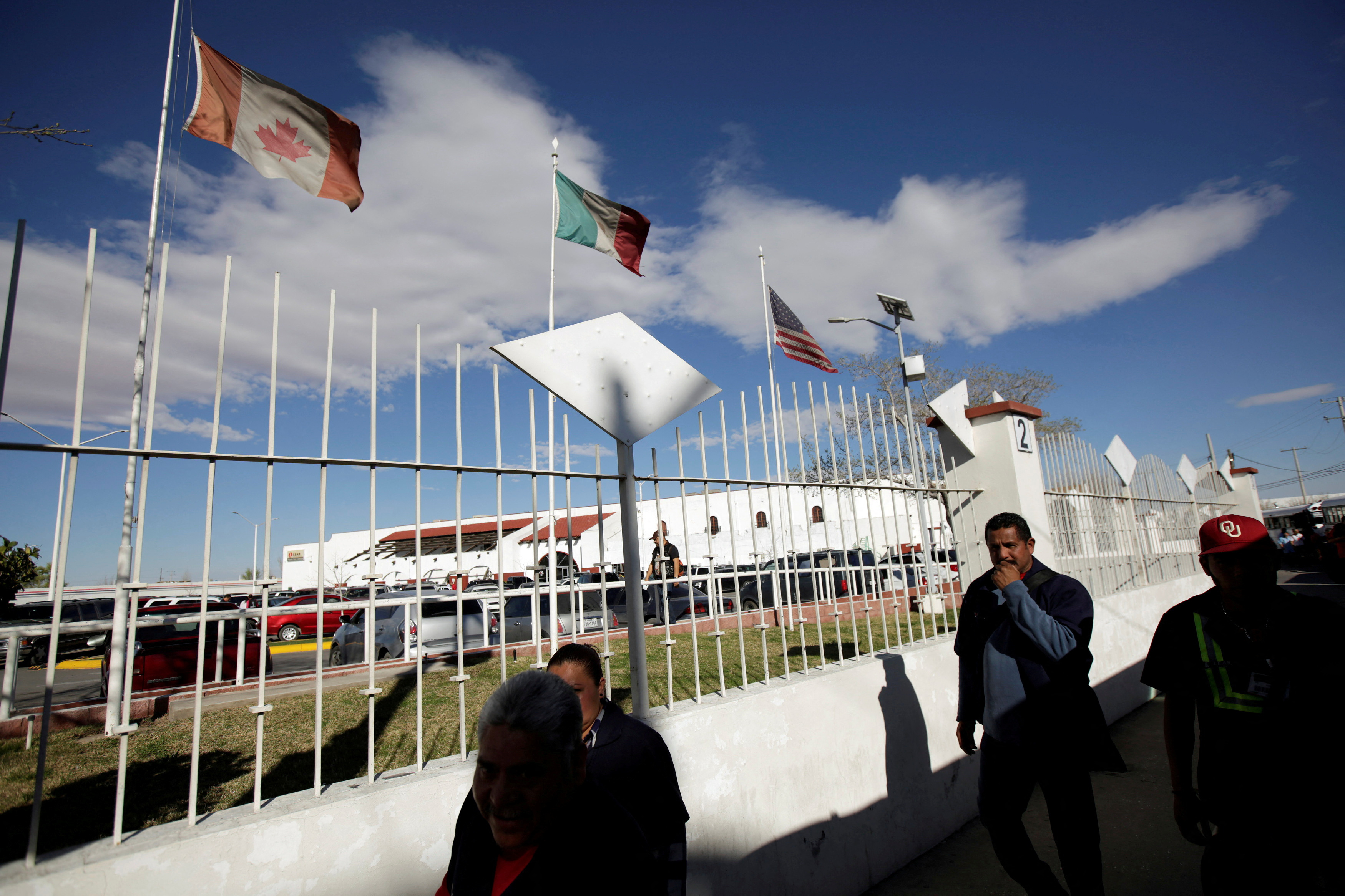 FILE PHOTO: Workers walk by the flags of Canada, Mexico and U.S. flying at an assembly factory in Ciudad Juarez