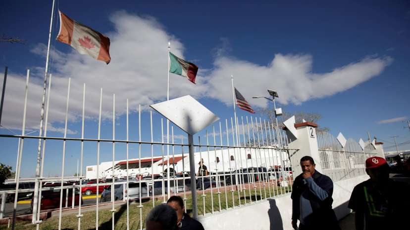FILE PHOTO: Workers walk by the flags of Canada, Mexico and U.S. flying at an assembly factory in Ciudad Juarez