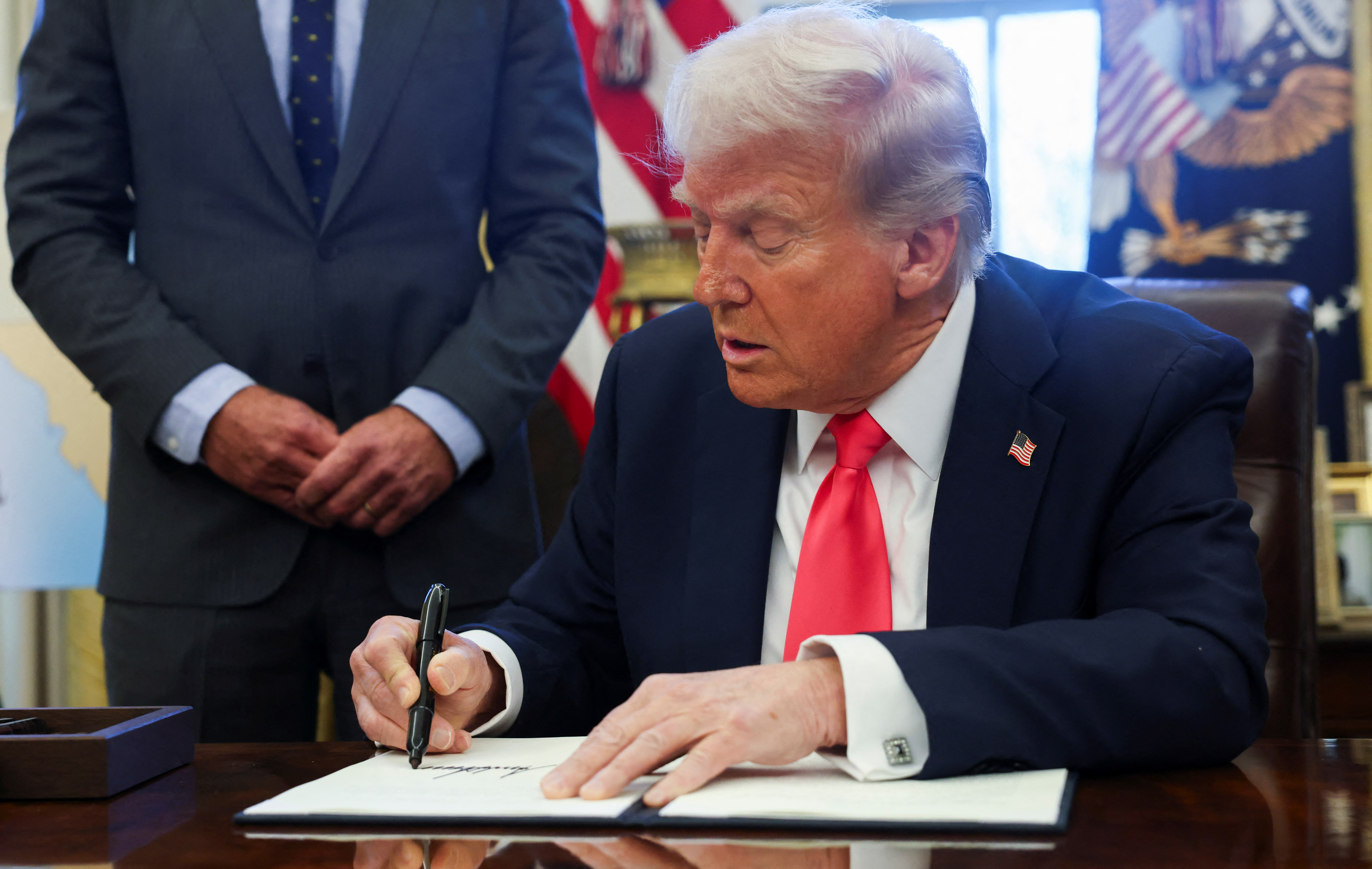U.S. President Donald Trump signs an executive order in the Oval Office, at the White House in Washington
