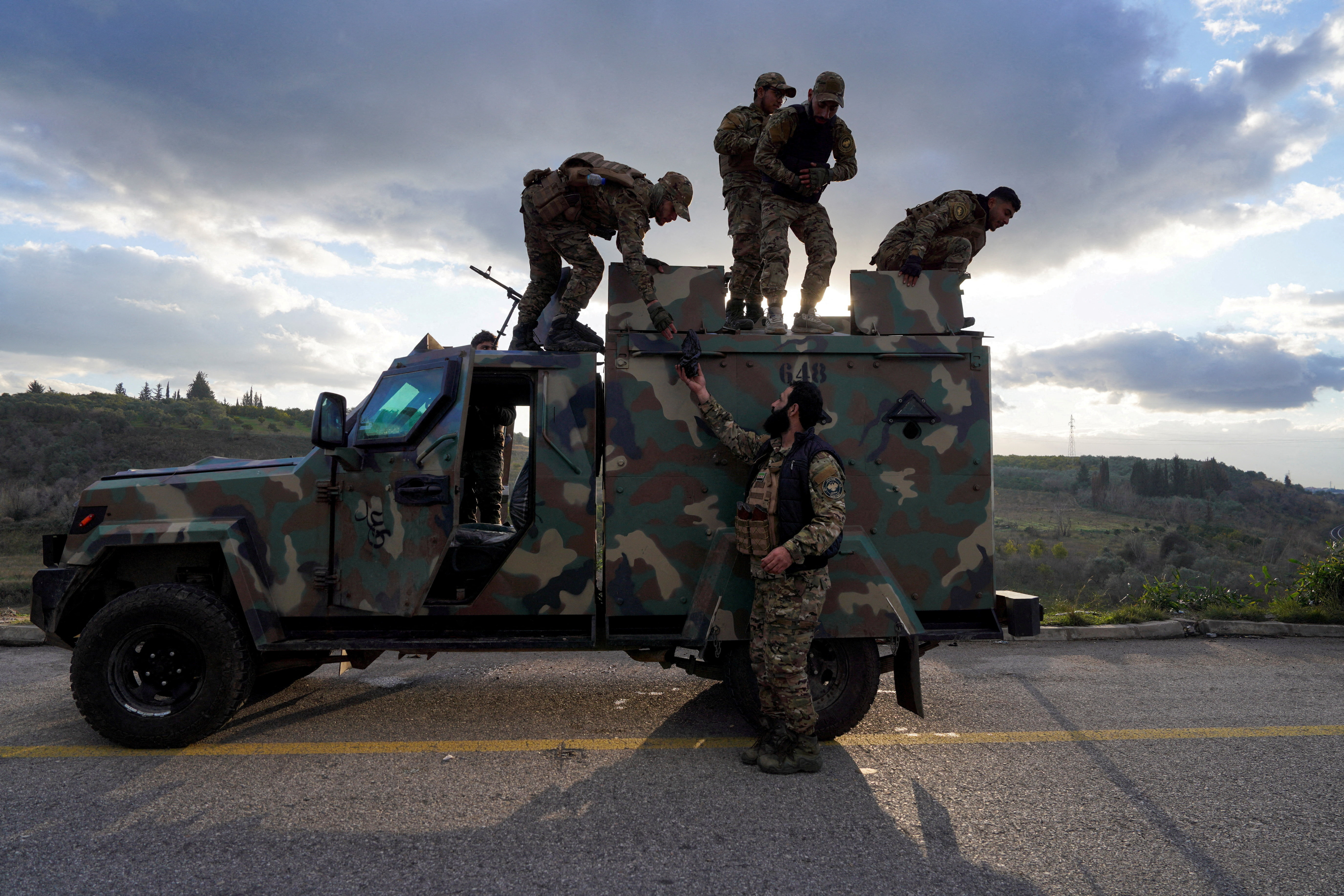 Members of the Syrian army stand on a military vehicle in Latakia