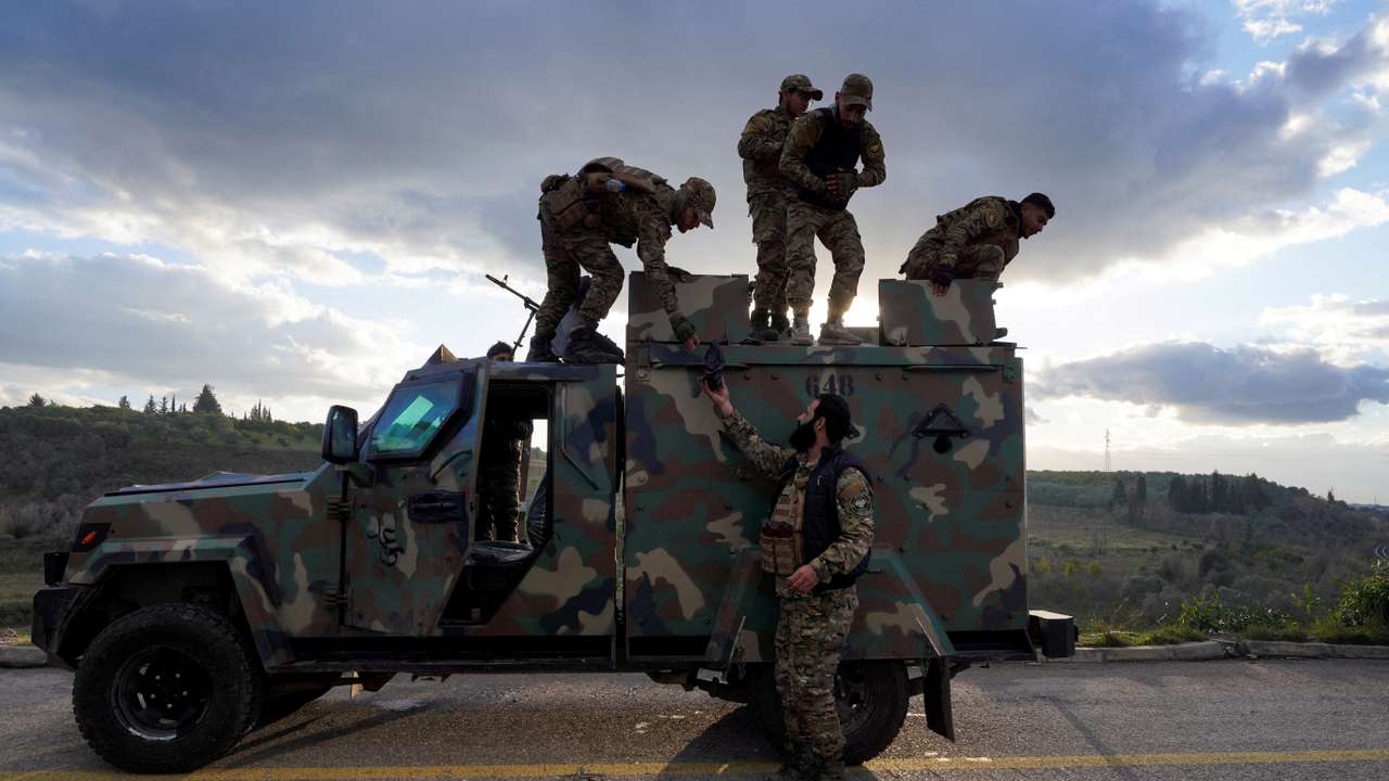 Members of the Syrian army stand on a military vehicle in Latakia