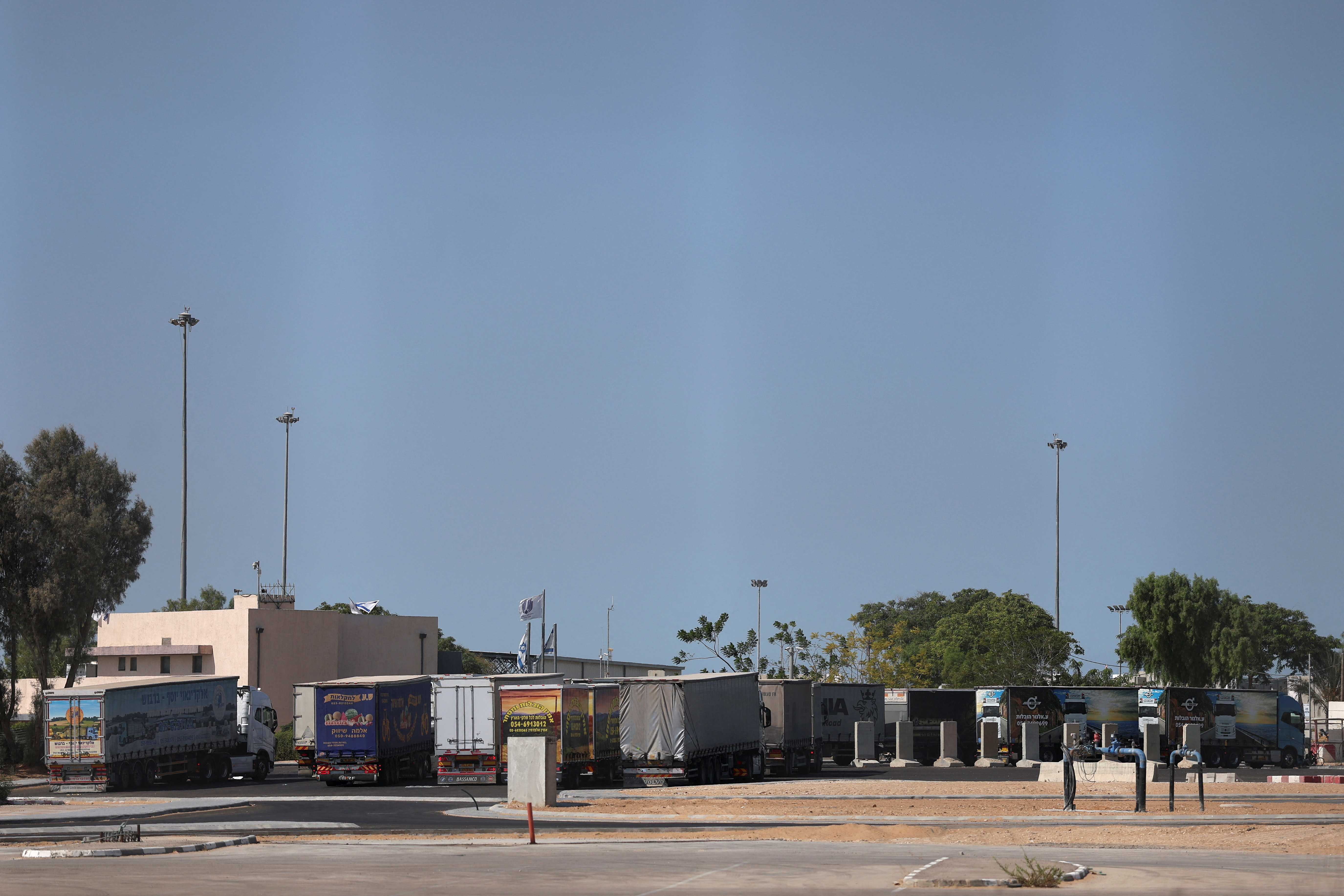 Trucks carrying aid wait at the Israeli side of the Kerem Shalom border crossing to southern Gaza