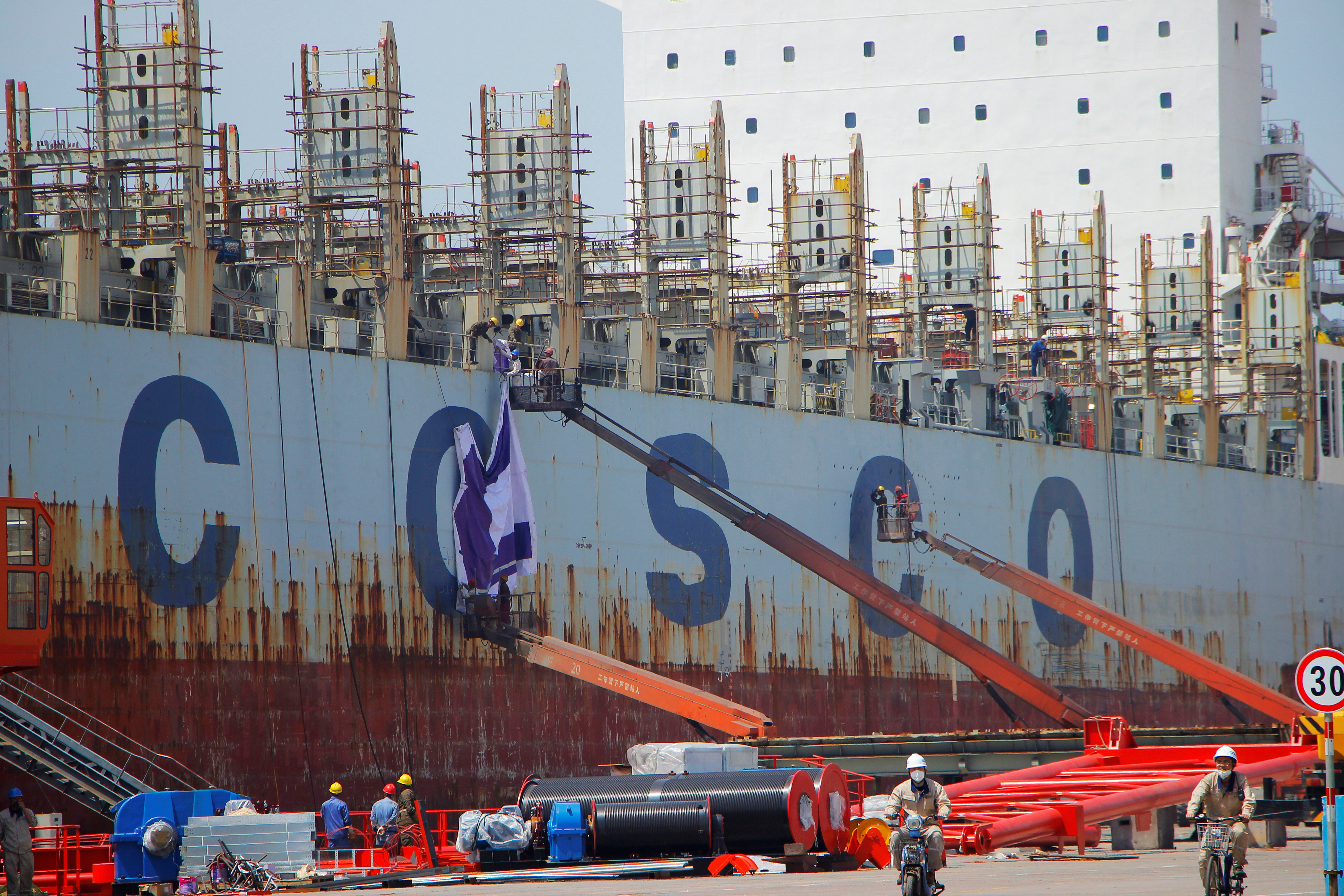 Men are seen working on a China Ocean Shipping Company (COSCO) vessel under construction at a shipyard in Weihai, Shandong