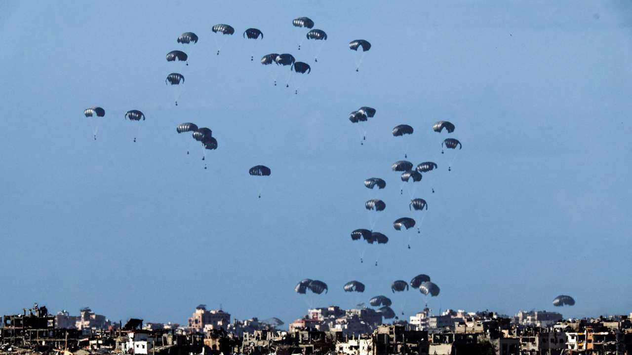 Packages dropped from a military aircraft fall towards northern Gaza, as seen from Israel