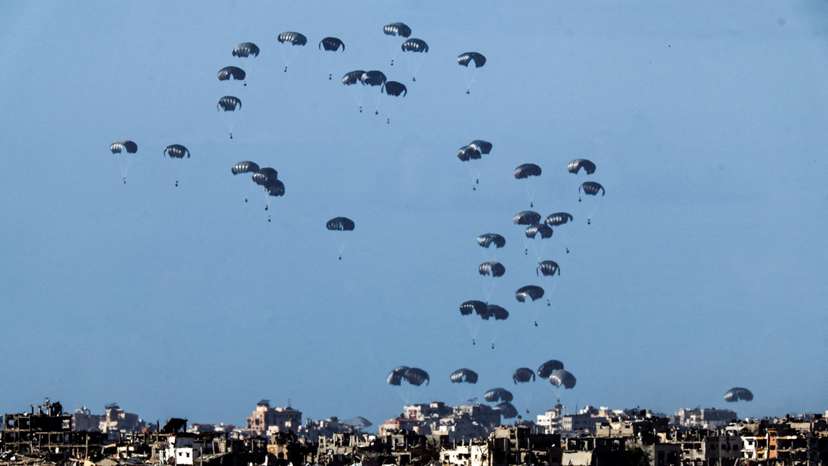 Packages dropped from a military aircraft fall towards northern Gaza, as seen from Israel