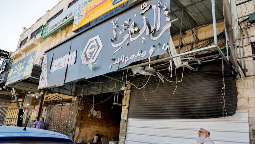 A man walks past a closed exchange office building that was damaged and targeted during an Israeli military operation, in Tulkarm