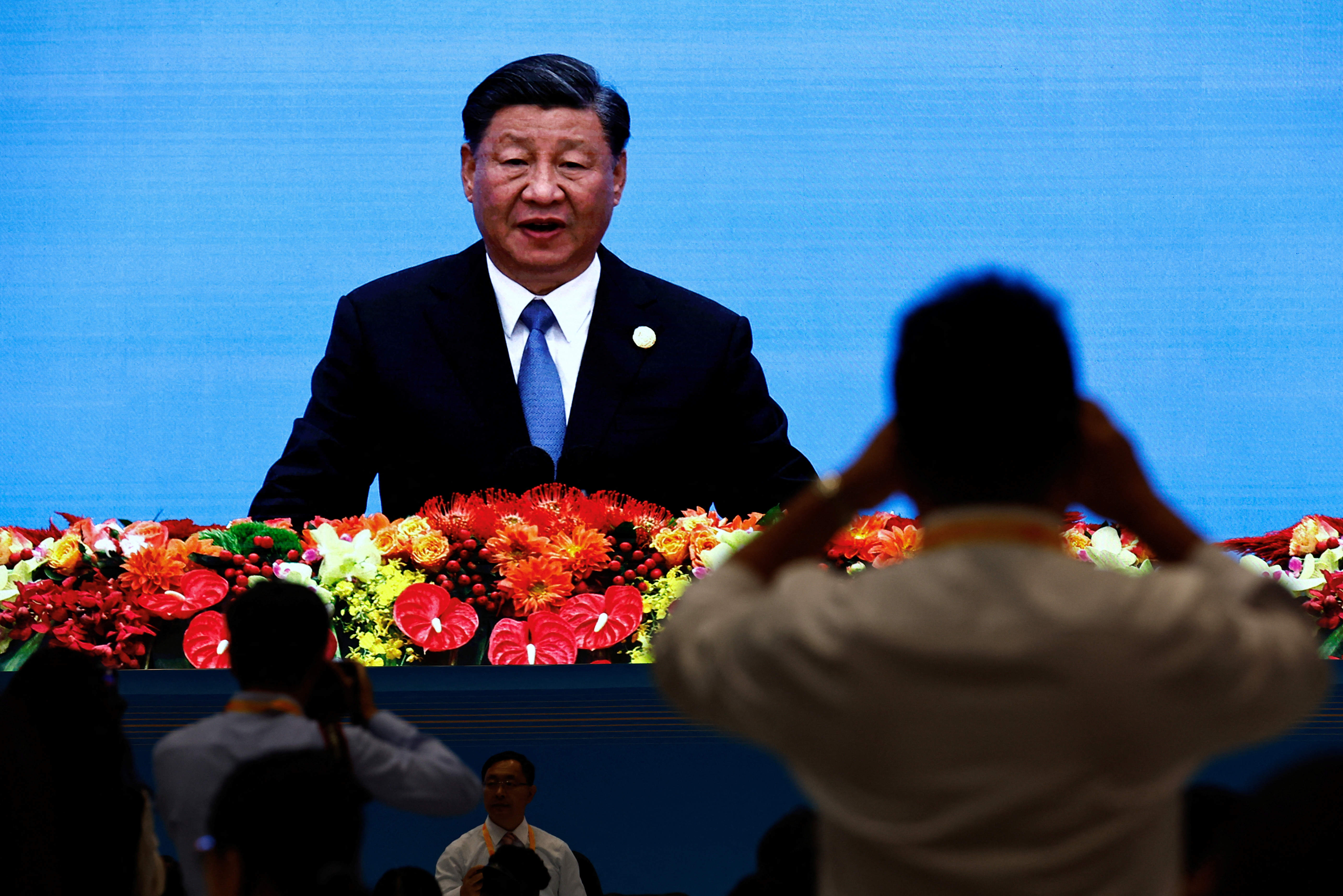 Journalists watch a giant screen broadcasting footage of Chinese President Xi Jinping at the opening ceremony of BRF in Beijing