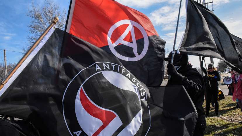 Members of the Great Lakes anti-fascist organization (Antifa) fly flags during a protest against the Alt-right outside a hotel in Warren, Michigan
