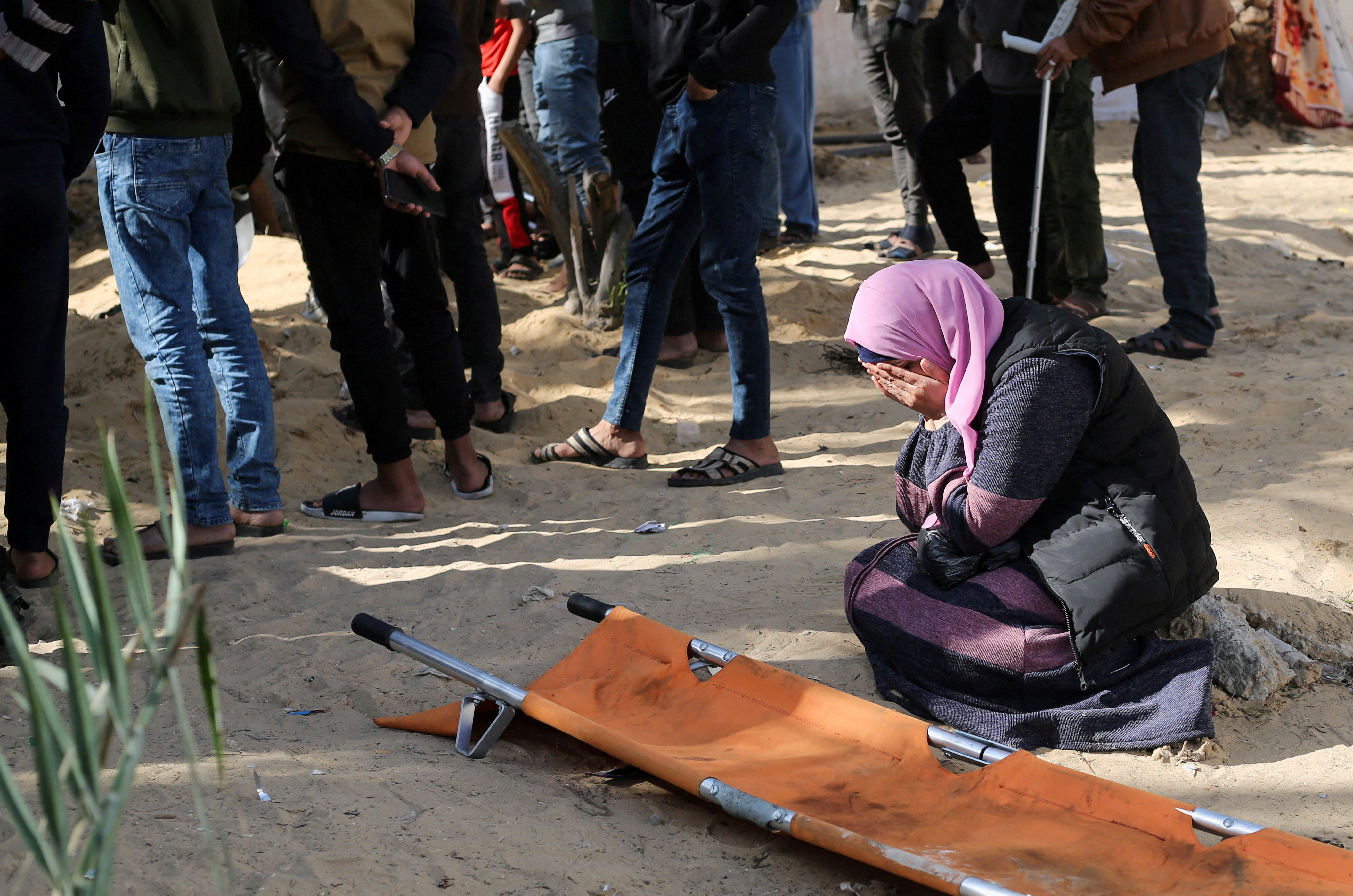 A woman reacts while people bury bodies of Palestinians killed in an Israeli strike, at the Nasser hospital premises