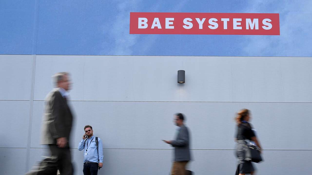 FILE PHOTO: Trade visitors walk past an advertisement for BAE Systems at Farnborough International Airshow in Farnborough, Britain