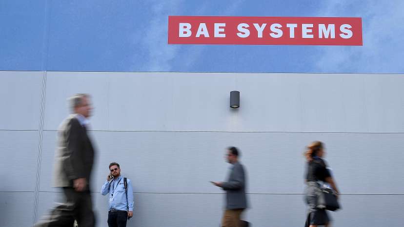 FILE PHOTO: Trade visitors walk past an advertisement for BAE Systems at Farnborough International Airshow in Farnborough, Britain