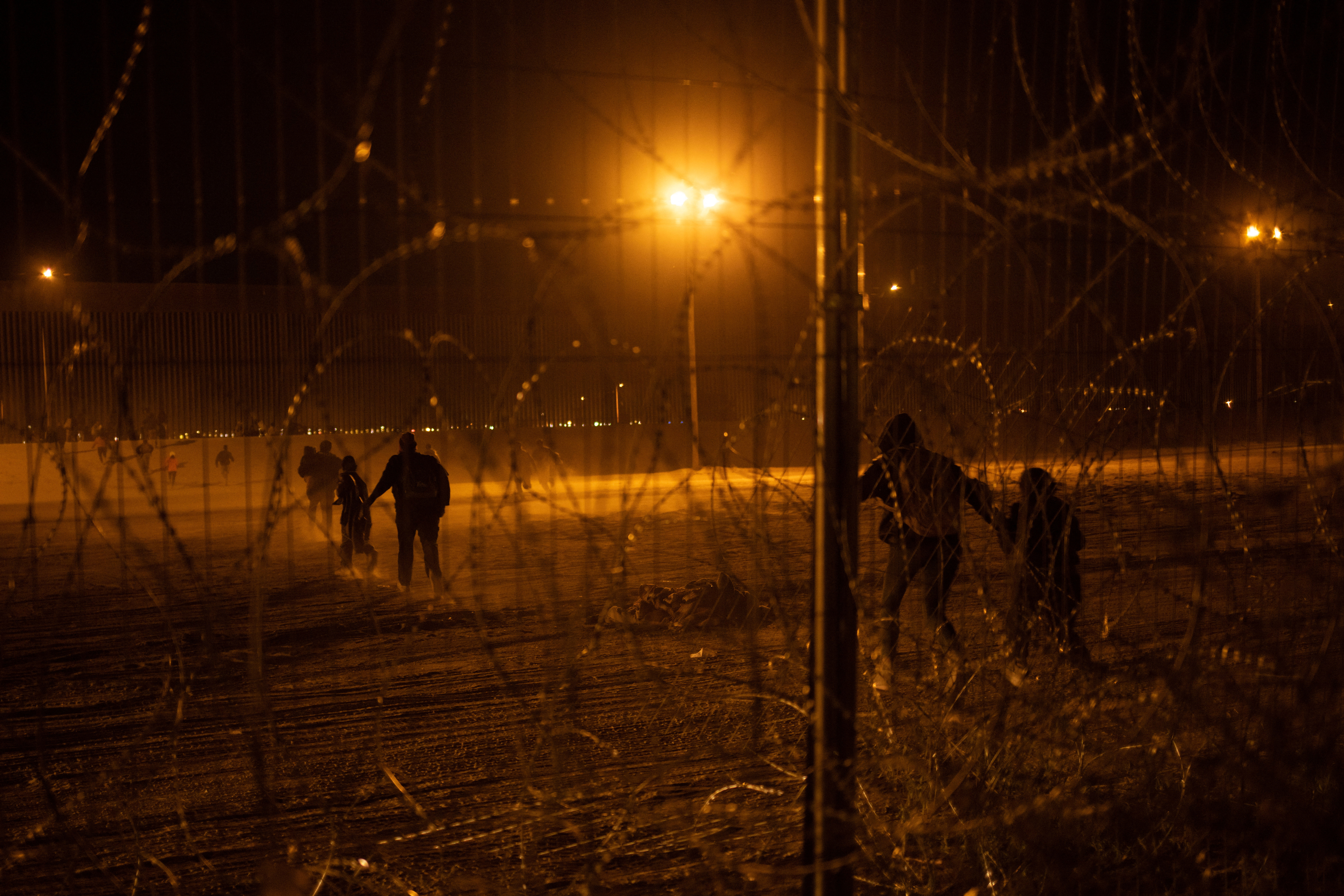 Migrants race towards border wall after breaching fence into the U.S. from Mexico
