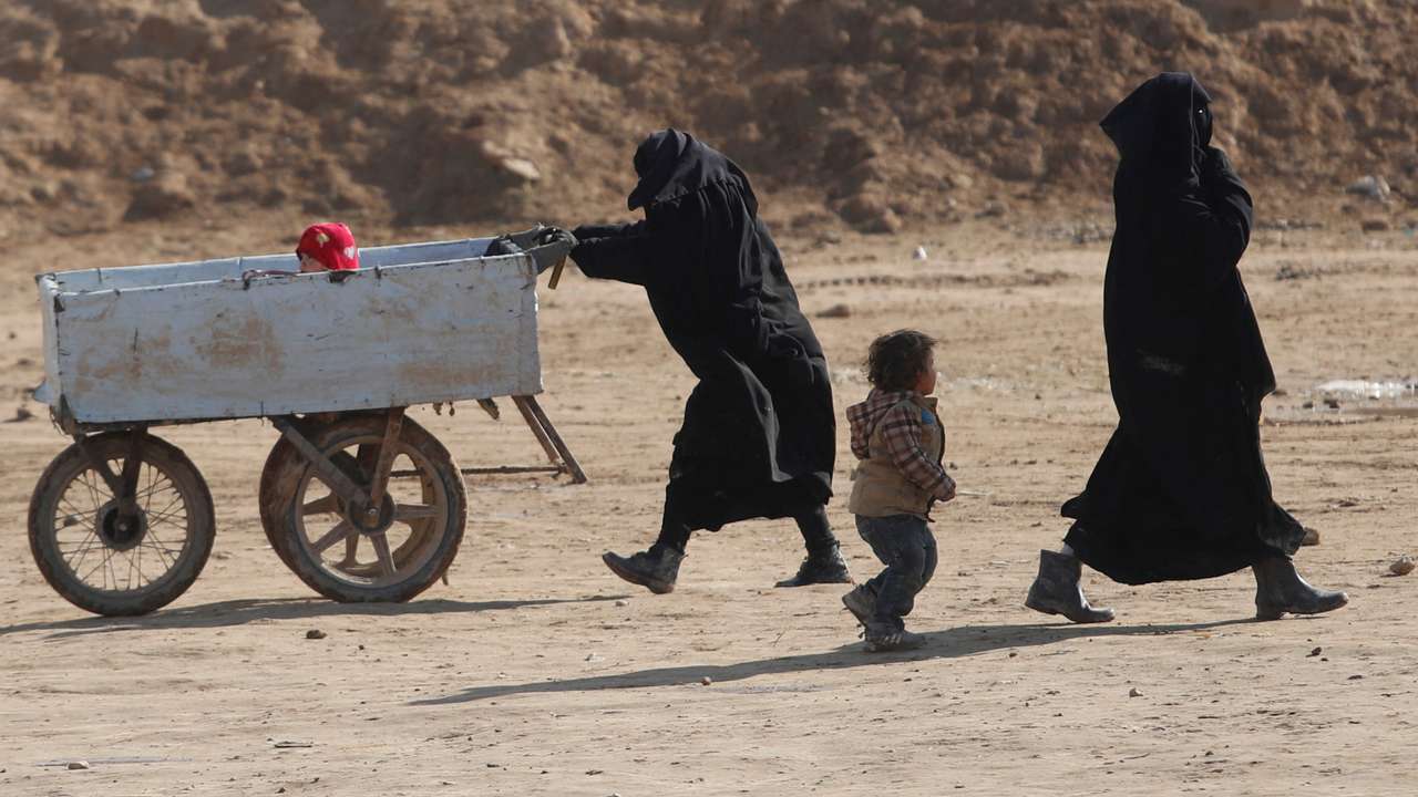 FILE PHOTO: Women and children walk through al-Hol camp in Syria