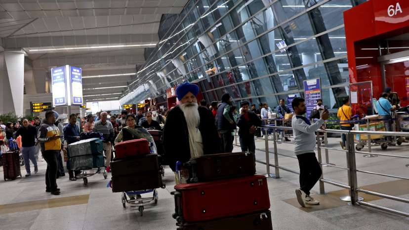 Travellers push trolleys with their luggage at the departure area of the Indira Gandhi International Airport in New Delhi