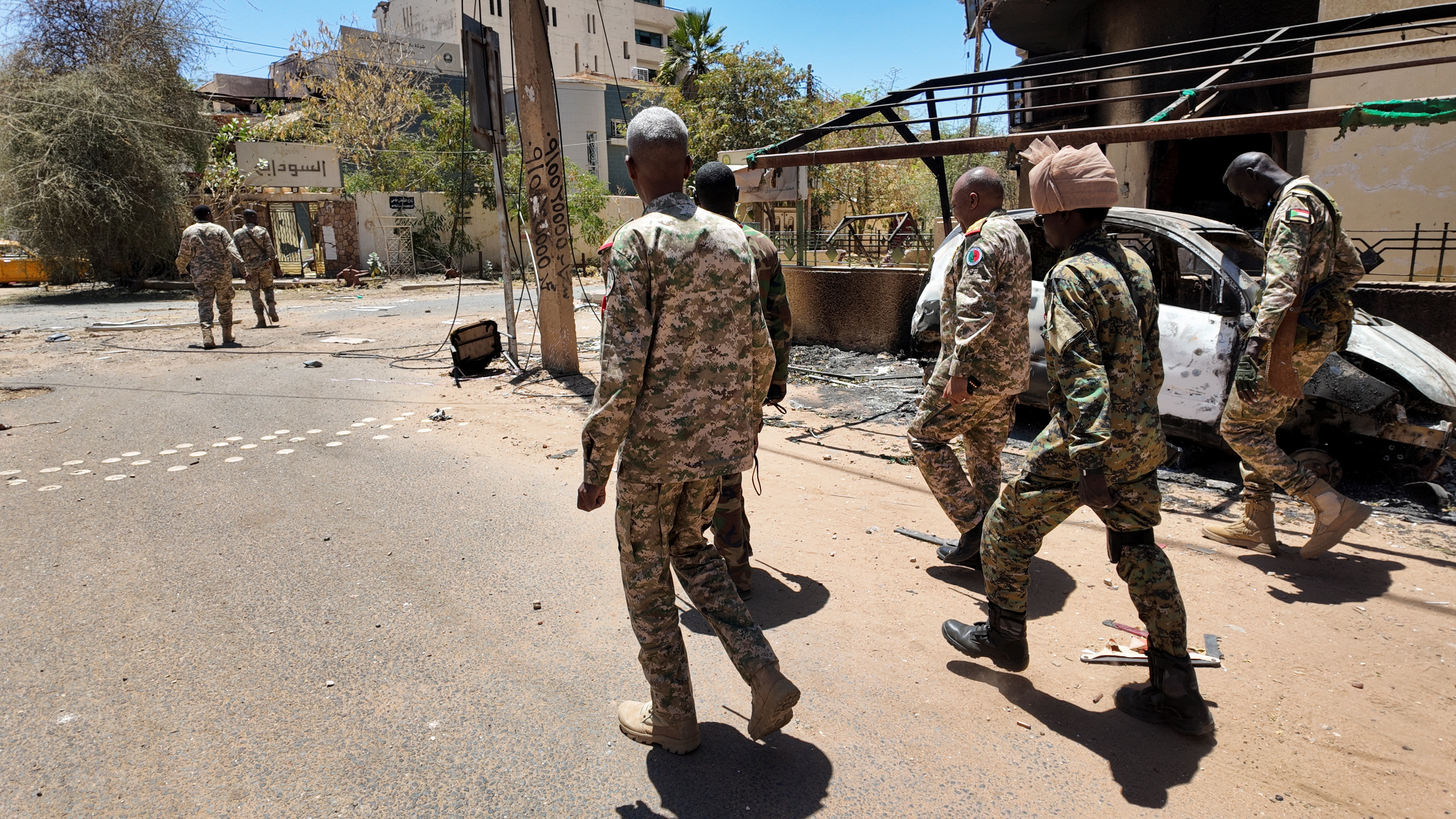 Members of the Sudanese army walk next to destroyed military vehicles after a battle with Rapid Support Forces (RSF) in the capital Khartoum, Sudan
