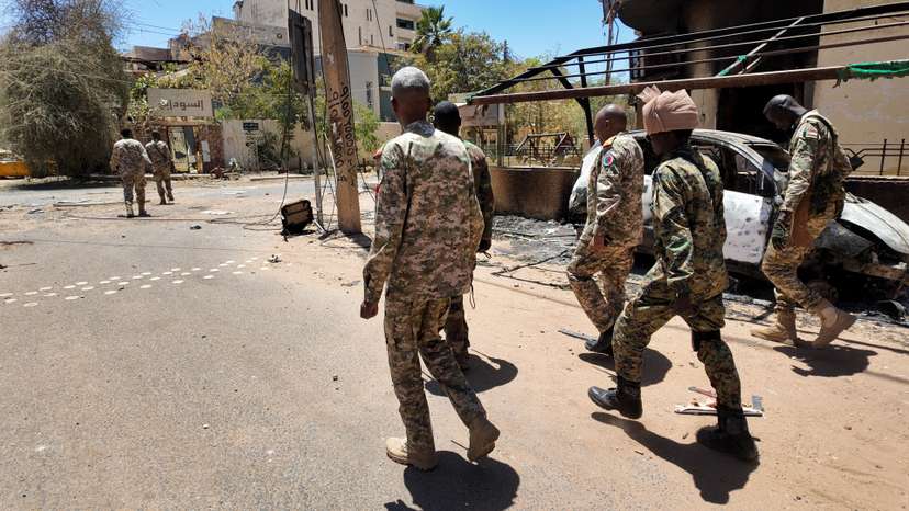 Members of the Sudanese army walk next to destroyed military vehicles after a battle with Rapid Support Forces (RSF) in the capital Khartoum, Sudan