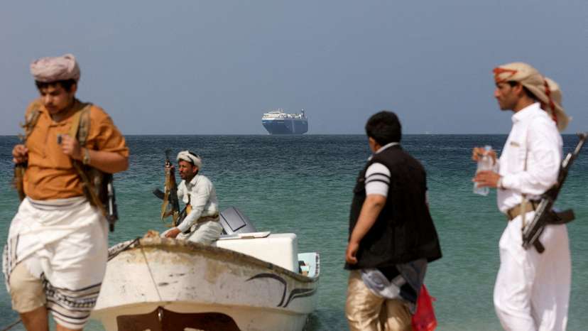 FILE PHOTO: Armed men stand on the beach as the Galaxy Leader commercial ship, seized by Yemen's Houthis last month, is anchored off the coast of al-Salif