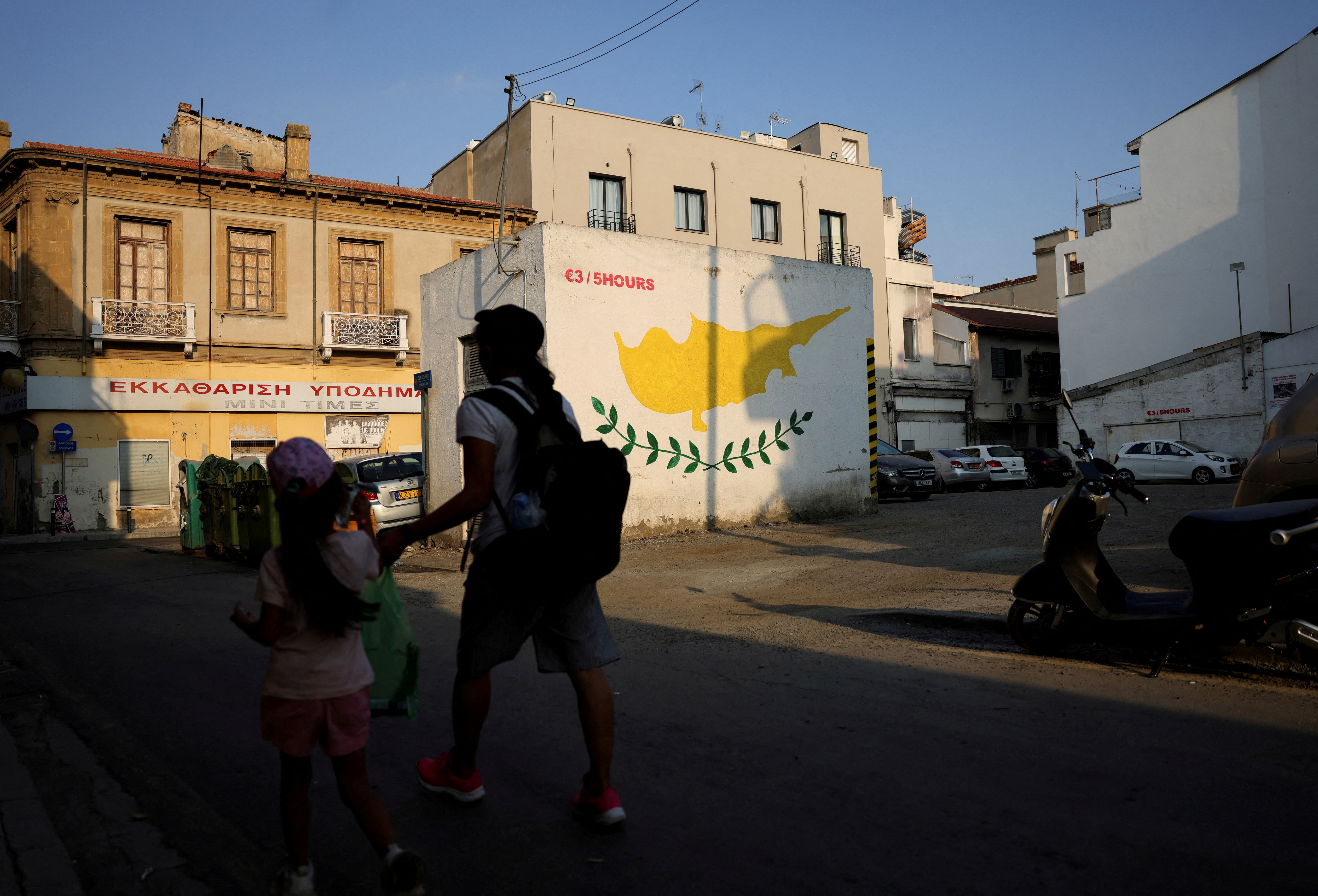 FILE PHOTO: People walk next to a Cypriot flag painted on a wall in Nicosia