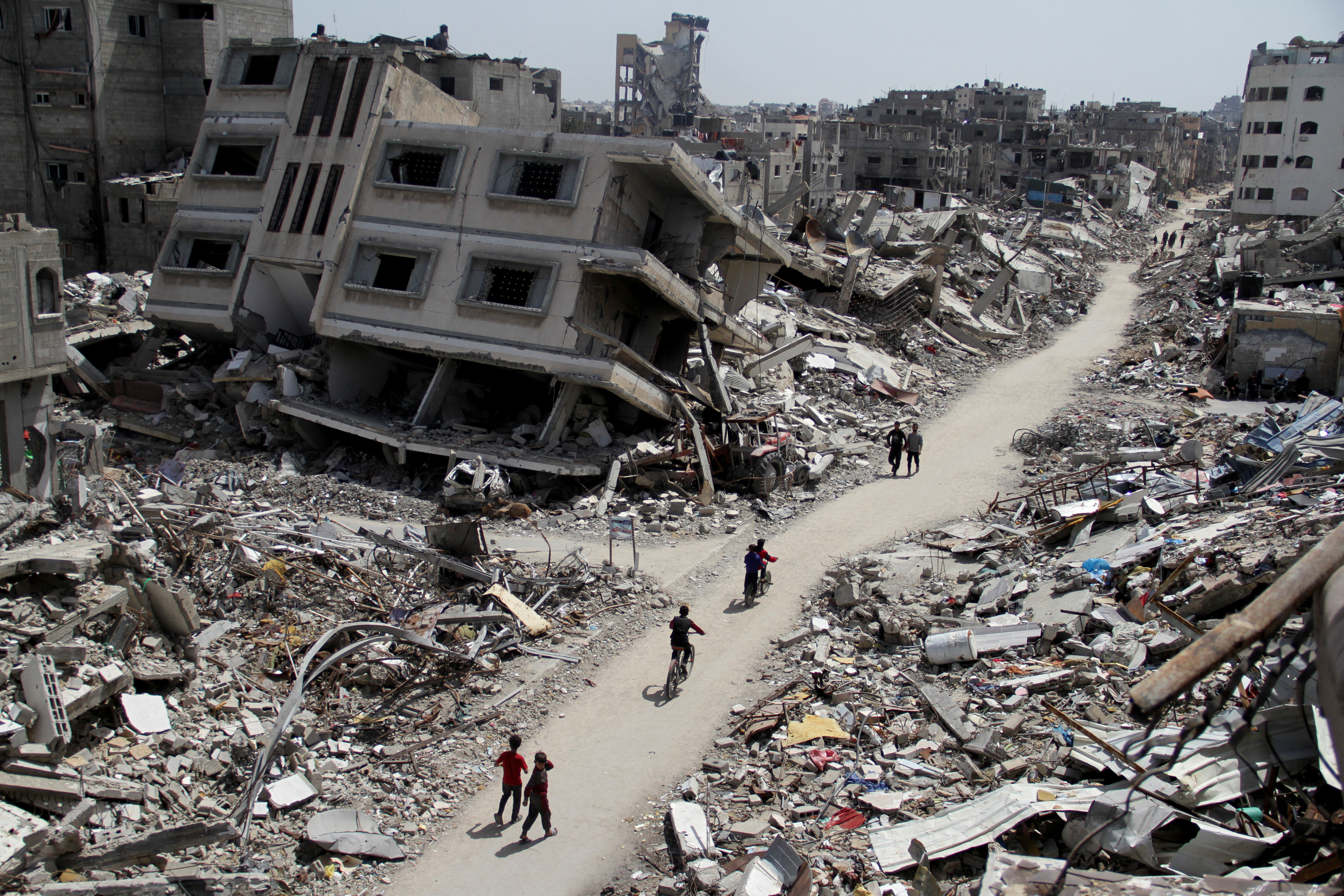 Palestinians ride bicycles past the ruins of houses and buildings destroyed during Israel’ military offensive, in the northern Gaza Strip