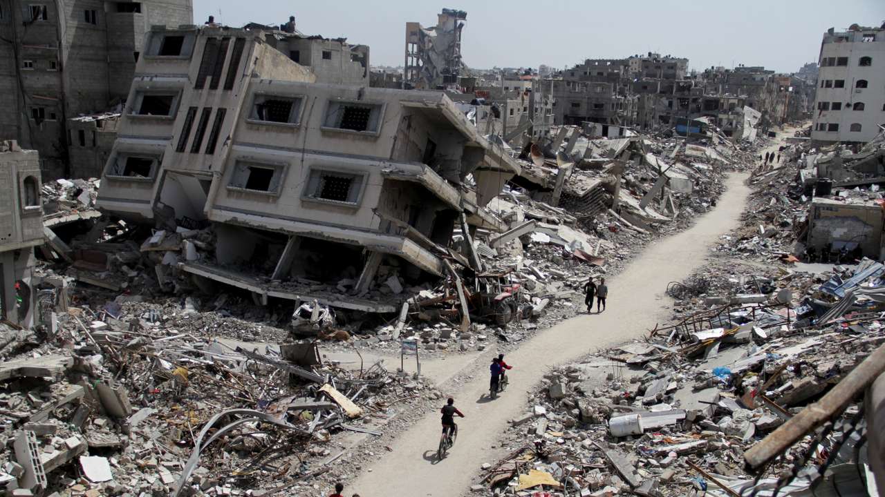 Palestinians ride bicycles past the ruins of houses and buildings destroyed during Israel’ military offensive, in the northern Gaza Strip