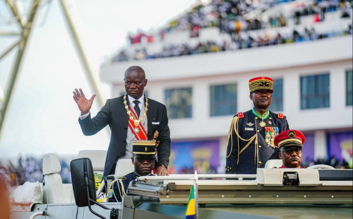 President of Gabon Brice Oligui Nguema Brice Oligui Nguema (L) waves to the crowd from a vehicle as he parades around the arena during his swearing-in ceremony at a stadium in Libreville on May 3, 2025. Gabon's Brice Oligui Nguema, whose coup ended 55 years of rule by the Bongo family, took oath as president on May 3, 2025 before a packed stadium and more than a dozen African leaders. (Photo by Nao Mukadi / AFP)