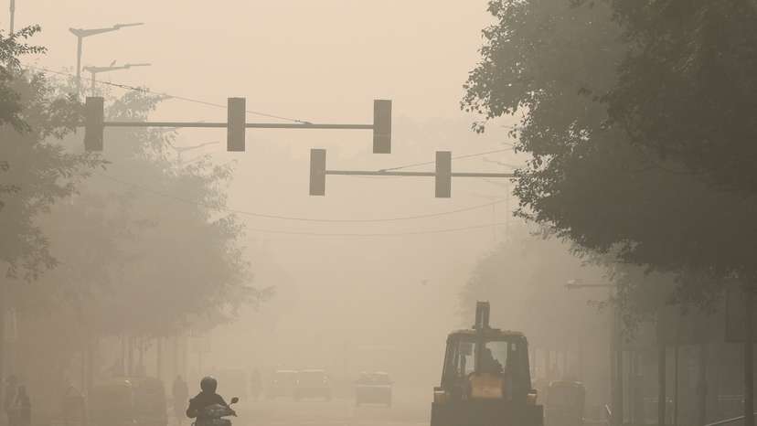A bulldozer is seen on a road, on a smoggy morning, in New Delhi
