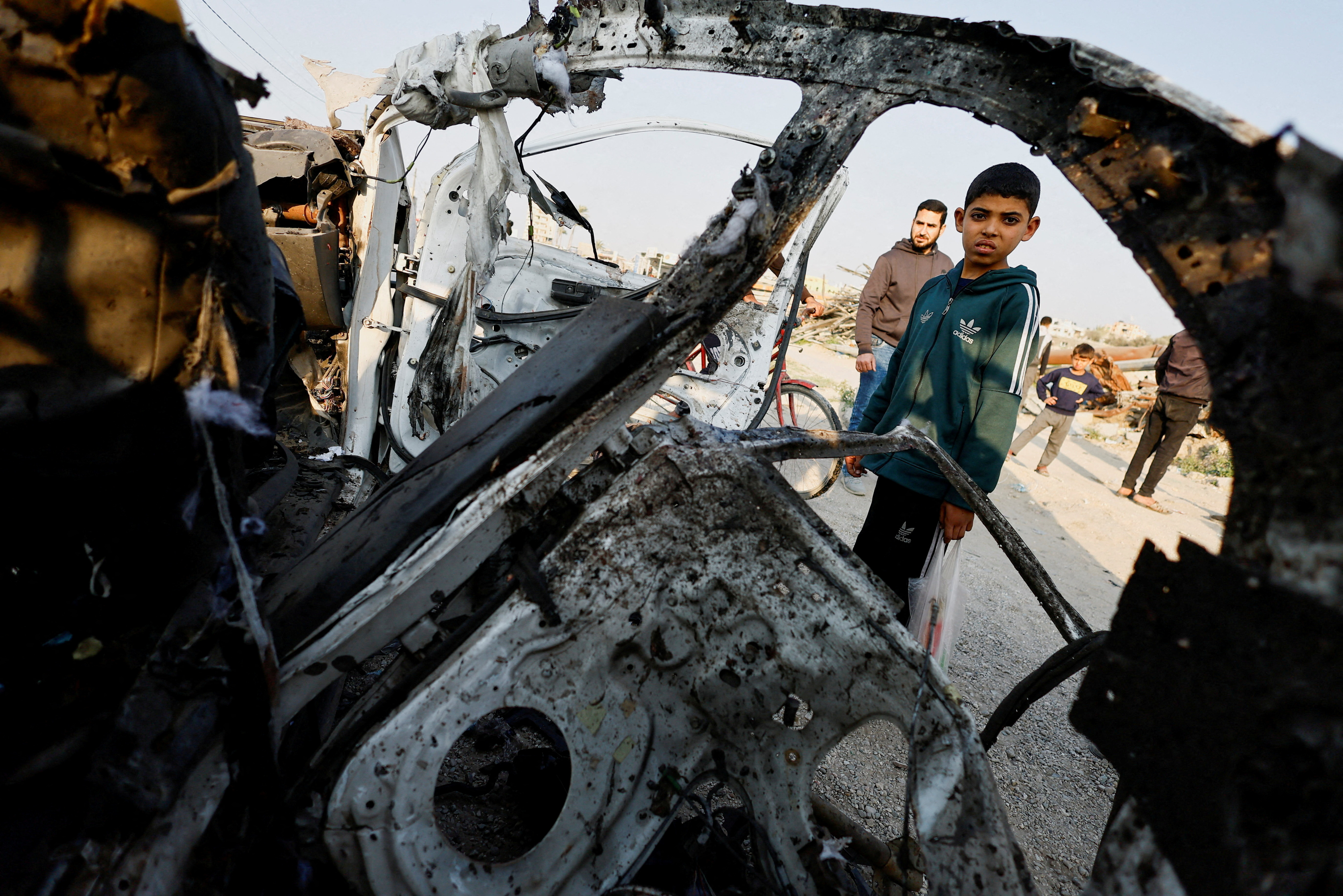 Palestinians inspect the site of an Israeli airstrike targeting a police vehicle in the central Gaza Strip
