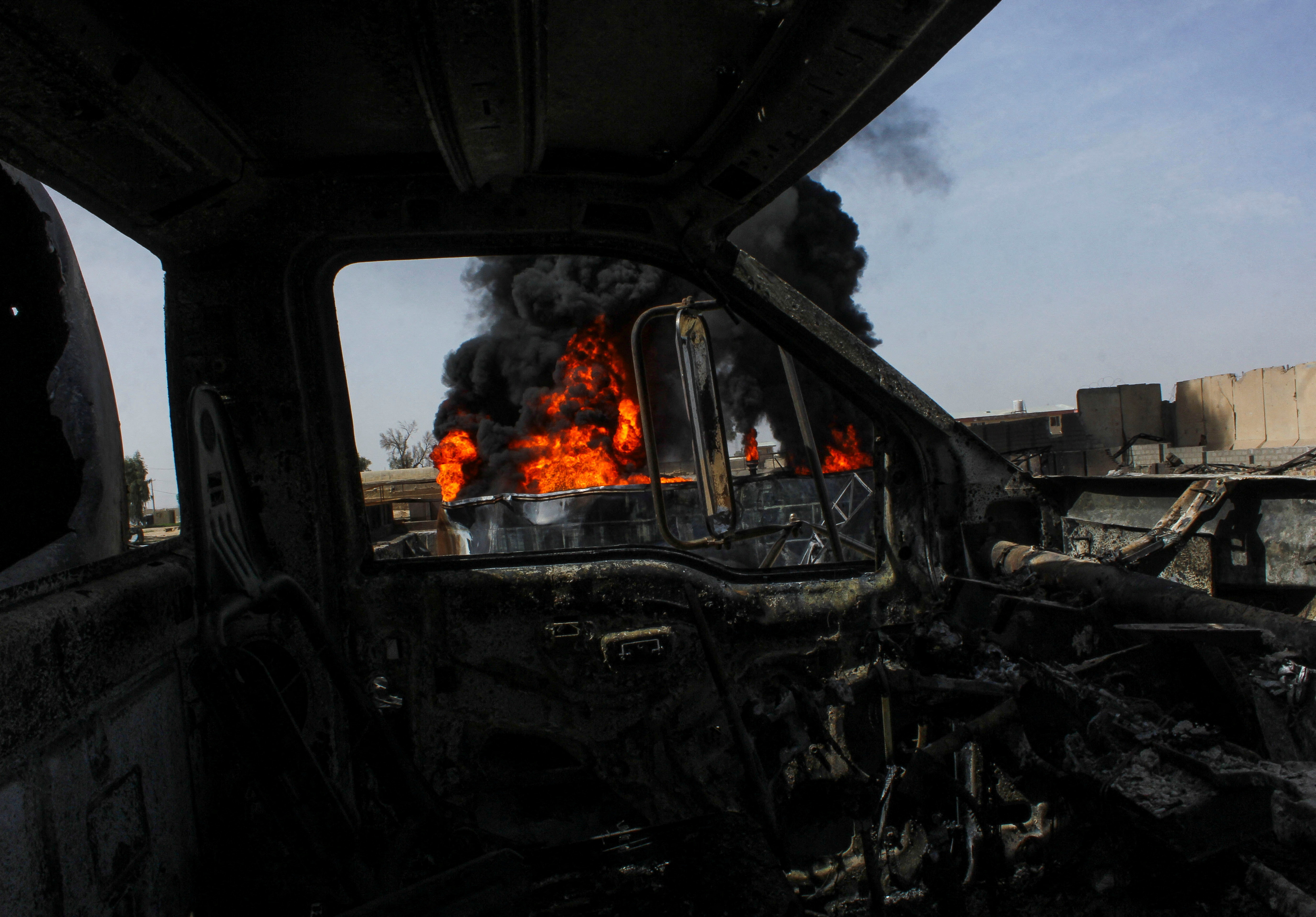 Thick black smoke is seen through a destroyed truck at private airline Kam Air's fuel depot after a strike in what the Taliban said was a Pakistani air strike, in Kandahar