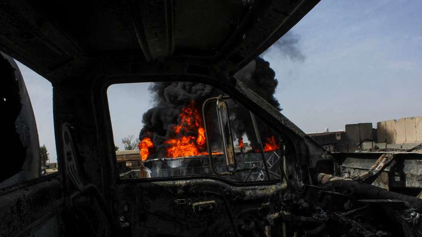 Thick black smoke is seen through a destroyed truck at private airline Kam Air's fuel depot after a strike in what the Taliban said was a Pakistani air strike, in Kandahar