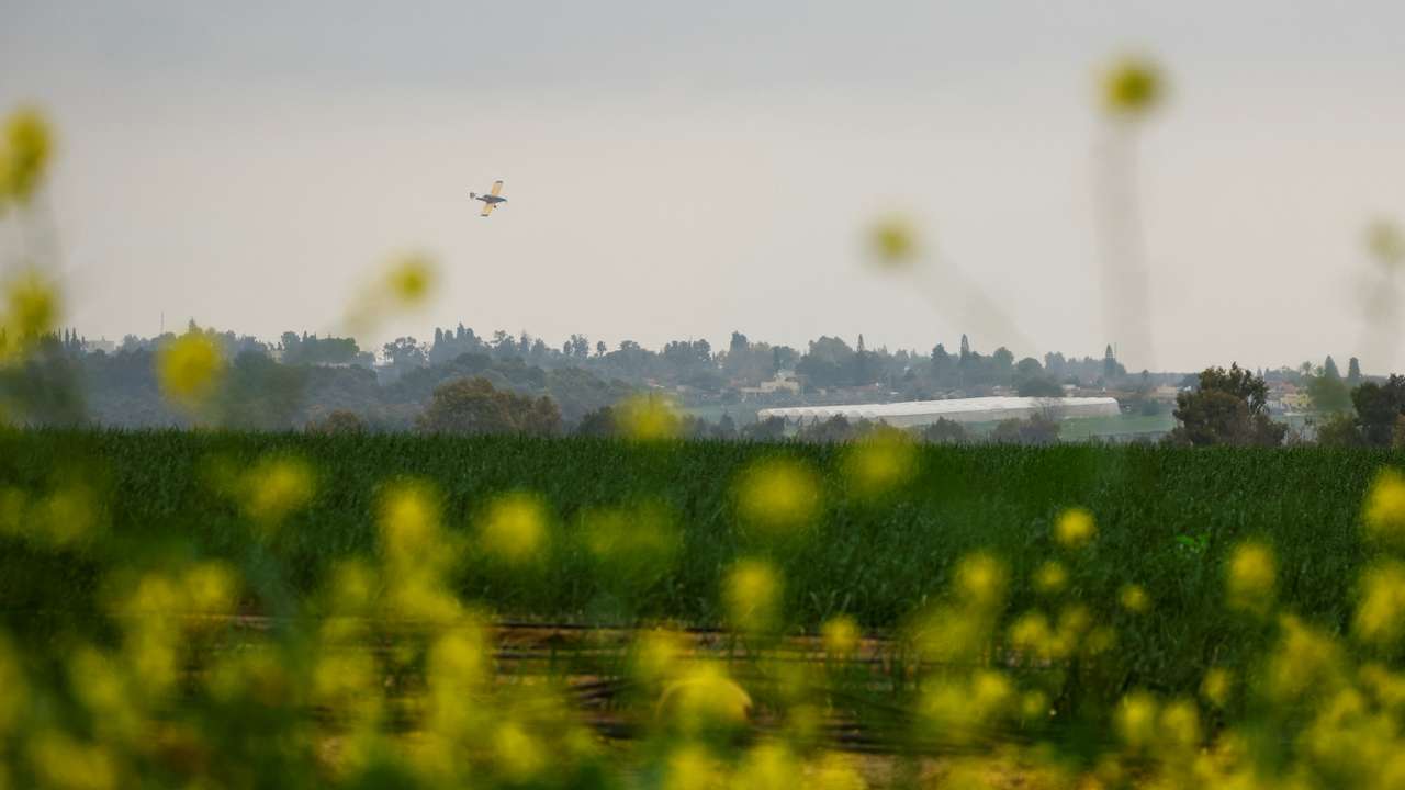 A crop duster plane flies over a field, near the Israel-Gaza border