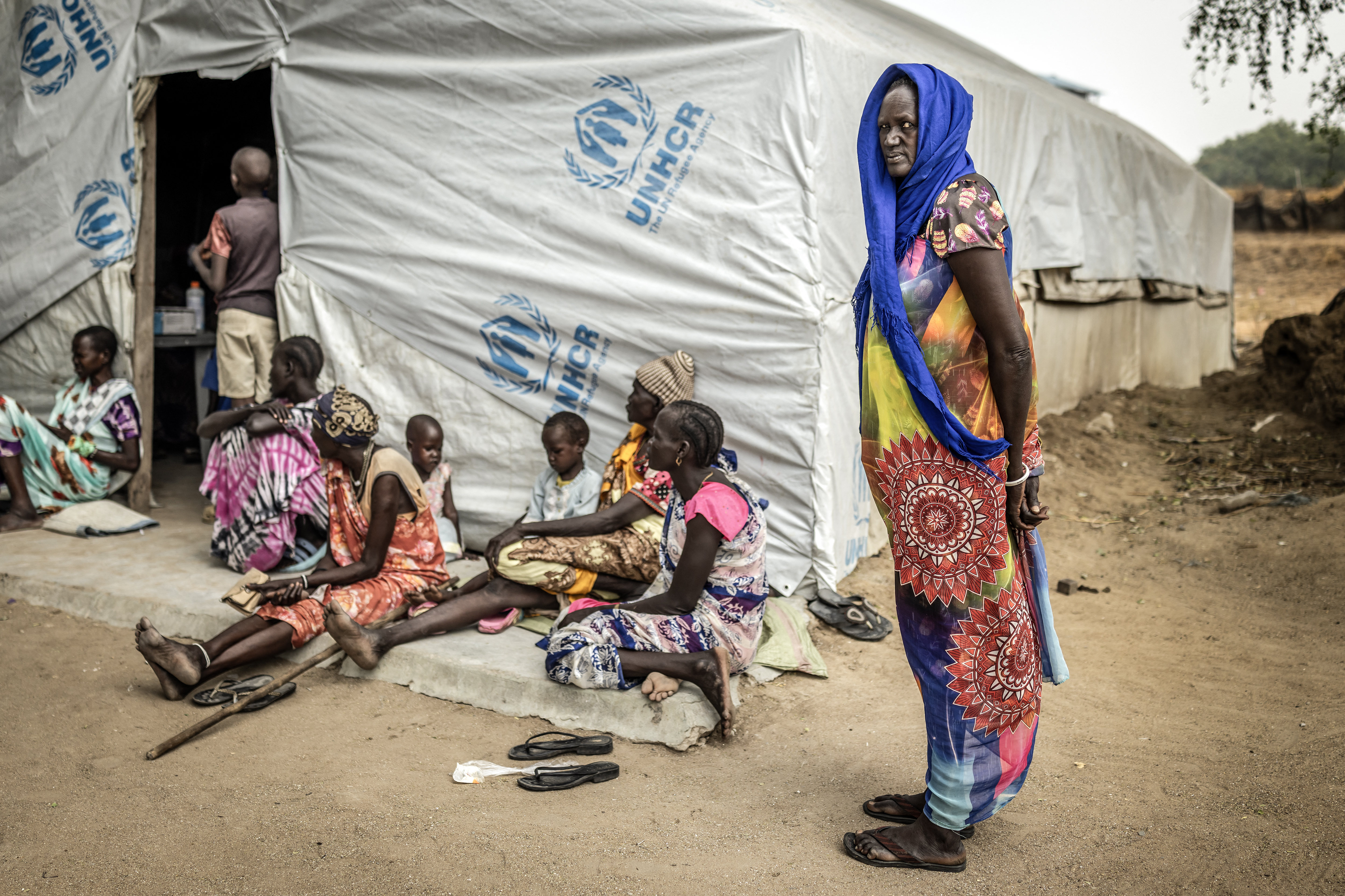 A displaced woman looks on as members of the Nuer community, uprooted by the conflict in Jonglei State, attend a community health session amid shortages of medical supplies in the POC IDP Camp in Bor, Jonglei State, on February 16, 2026. South Sudan gained independence in 2011 but quickly descended into civil war between rival generals, Salva Kiir and Riek Machar. A power-sharing deal in 2018 brought relative peace, with Kiir as president and Machar his deputy. But the deal was never fully implemented, their forces never unified, and elections never held. Over the past year, Machar has been jailed and violence has erupted between their forces in several areas. The worst has been in Jonglei state, where some 280,000 people have been displaced since December, according to the United Nations. (Photo by Luis TATO / AFP)